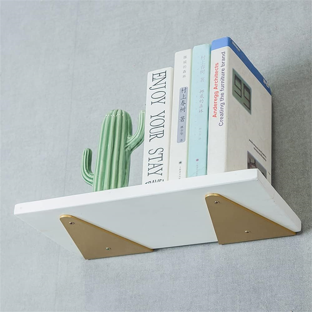 Weißes Regal mit Büchern und einem Kaktus vor einer grauen Wand.