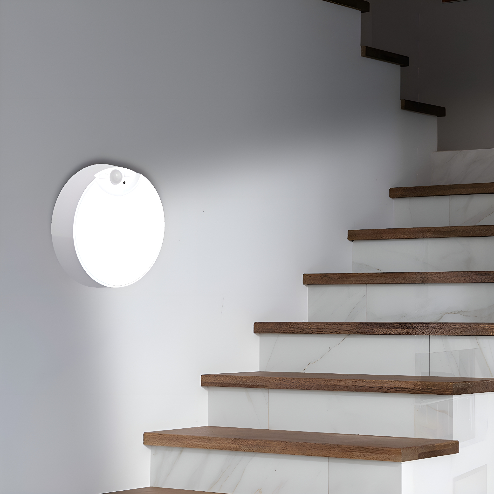 Eine weiße, runde Wandleuchte neben einer Treppe. Die Treppe hat Holzstufen und weiße Setzstufen.