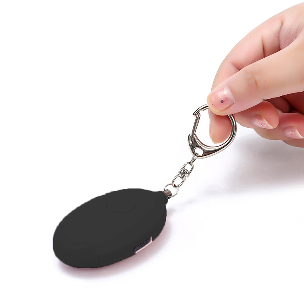 Schwarzes Alarmgerät mit Schlüsselanhänger, gehalten von einer Hand, weißer Hintergrund.