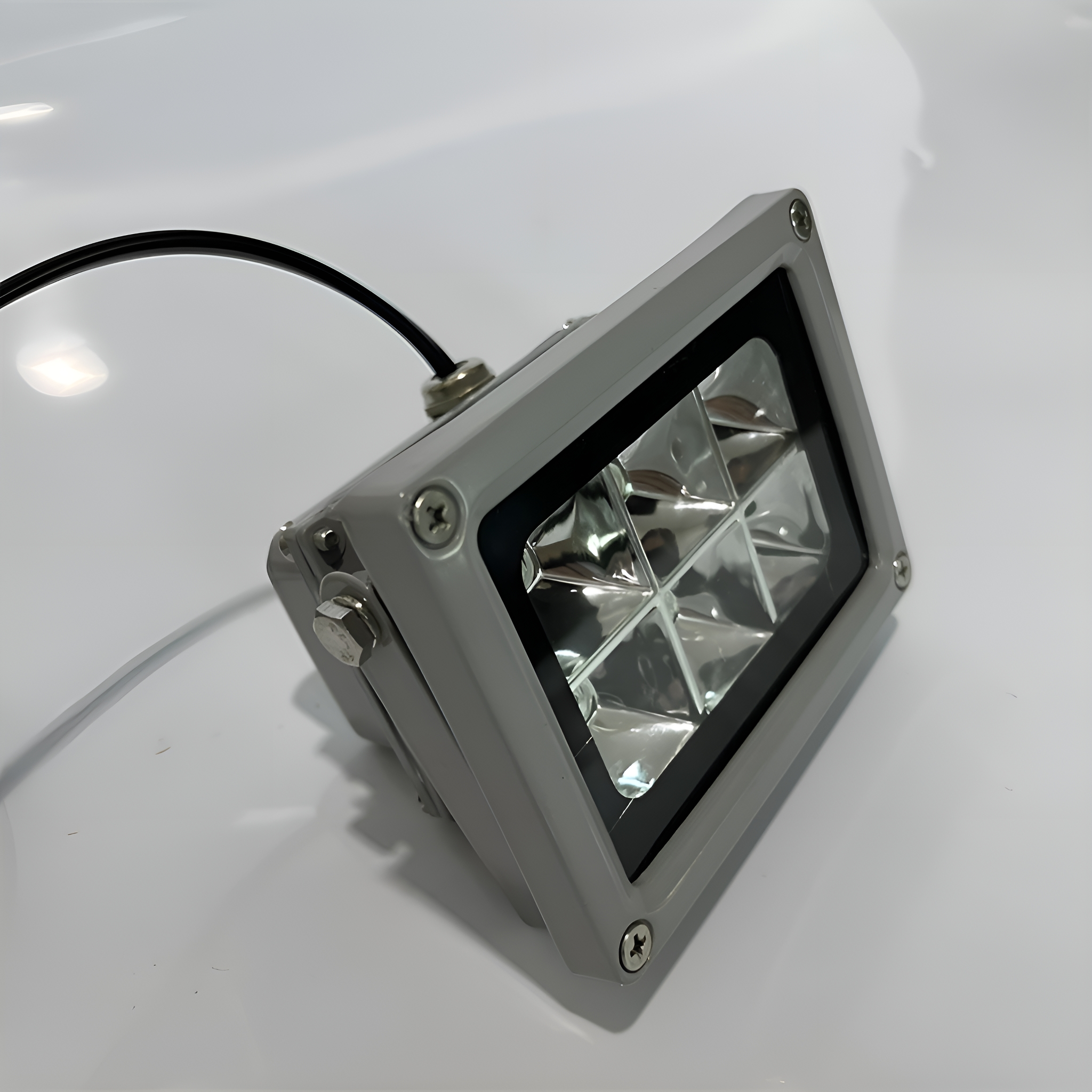 Ein graues rechteckiges LED-Licht. Es hat mehrere Linsen, Schrauben und ein schwarzes Kabel.