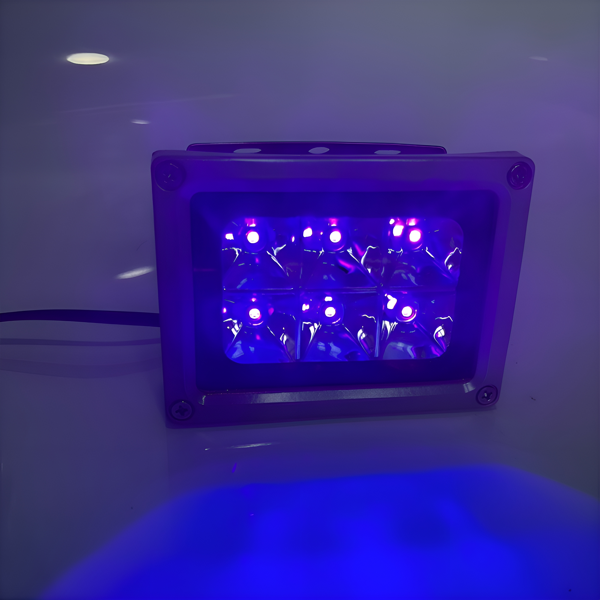 Quadratisches lila Licht mit mehreren hellen violetten Lichtern im Inneren, auf weißer Oberfläche.