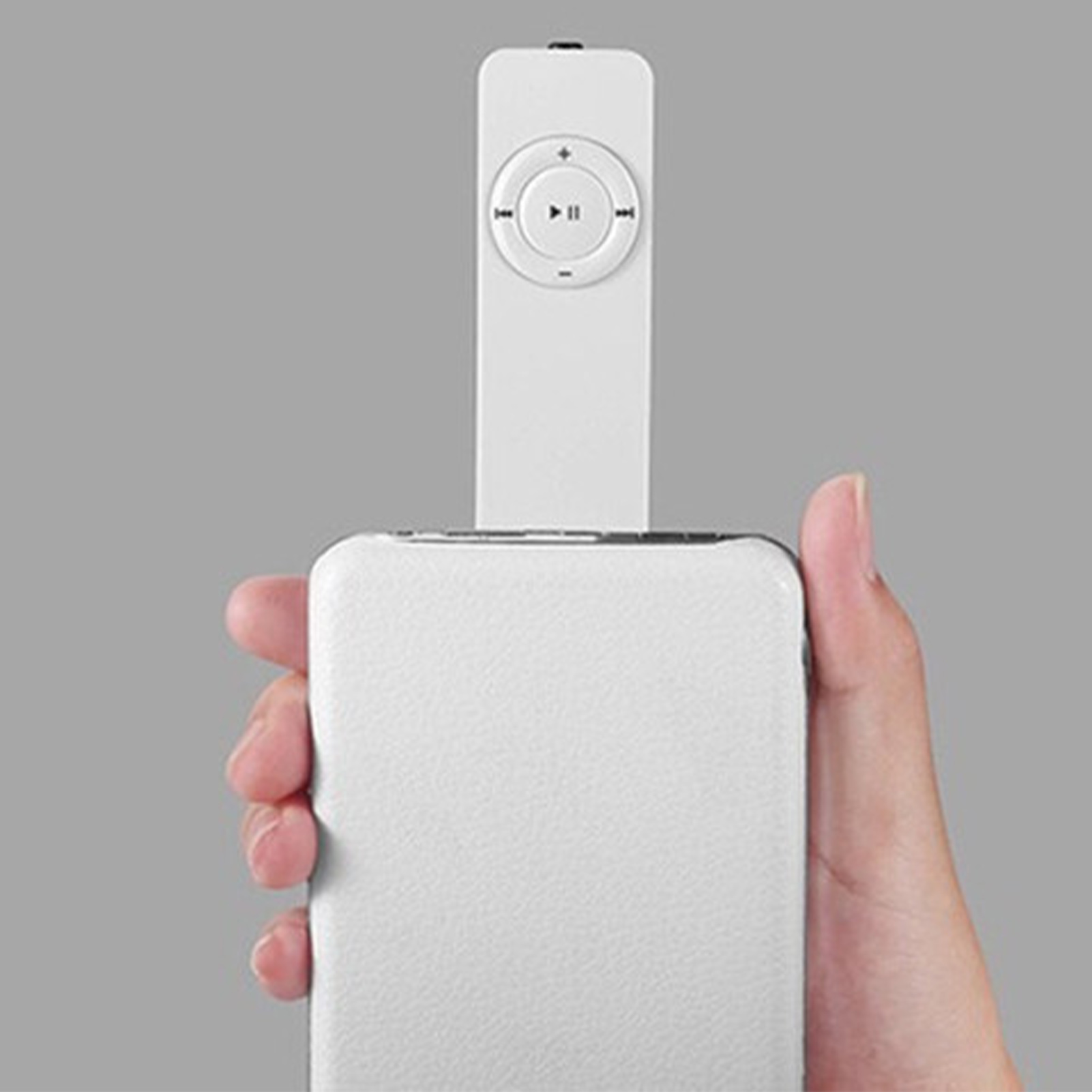 Ein weißes Smartphone, das von einer Hand gehalten wird, mit einer weißen Fernbedienung obenauf.