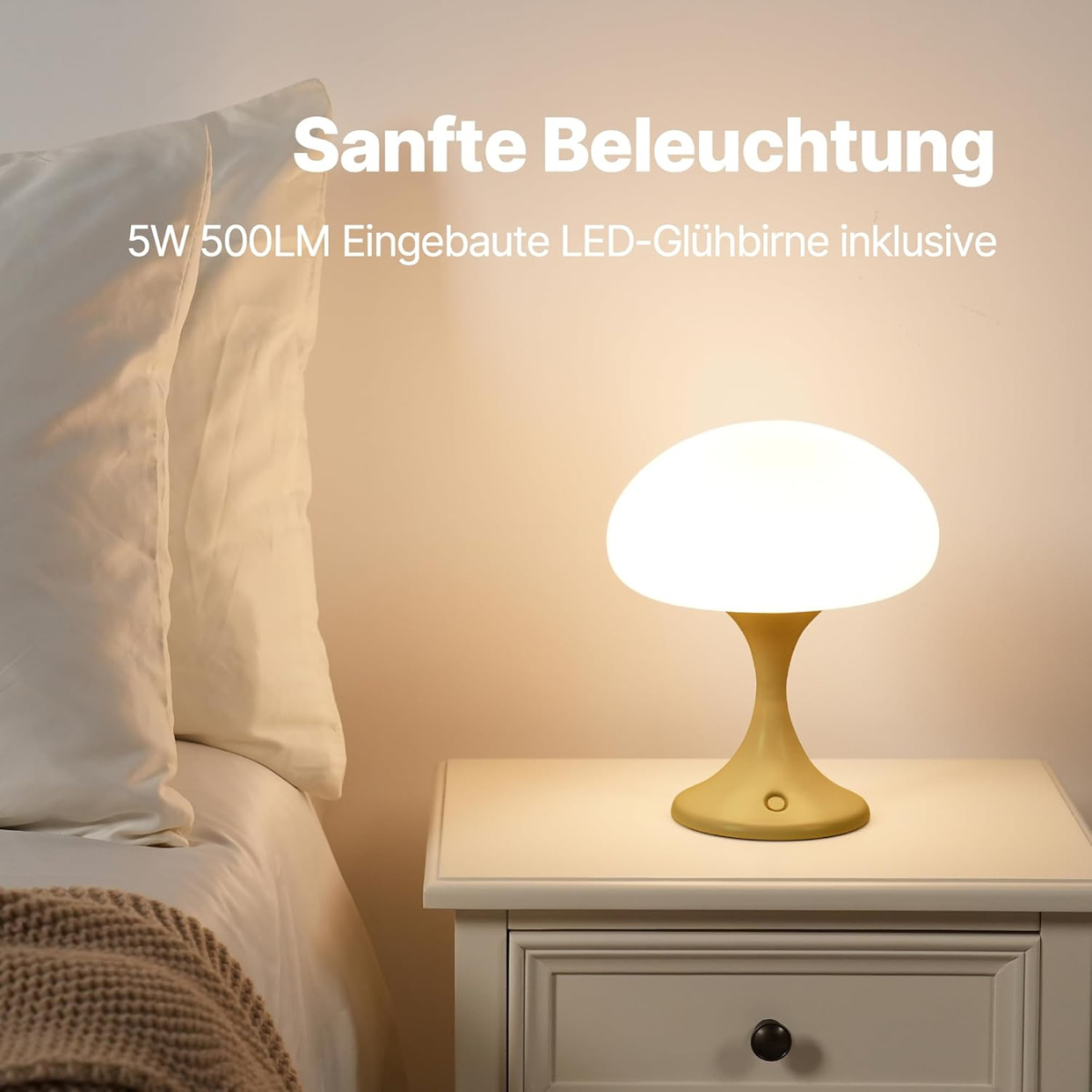 Eine pilzförmige Lampe auf einem weißen Nachttisch. Neben einem weißen Bett mit Kissen.