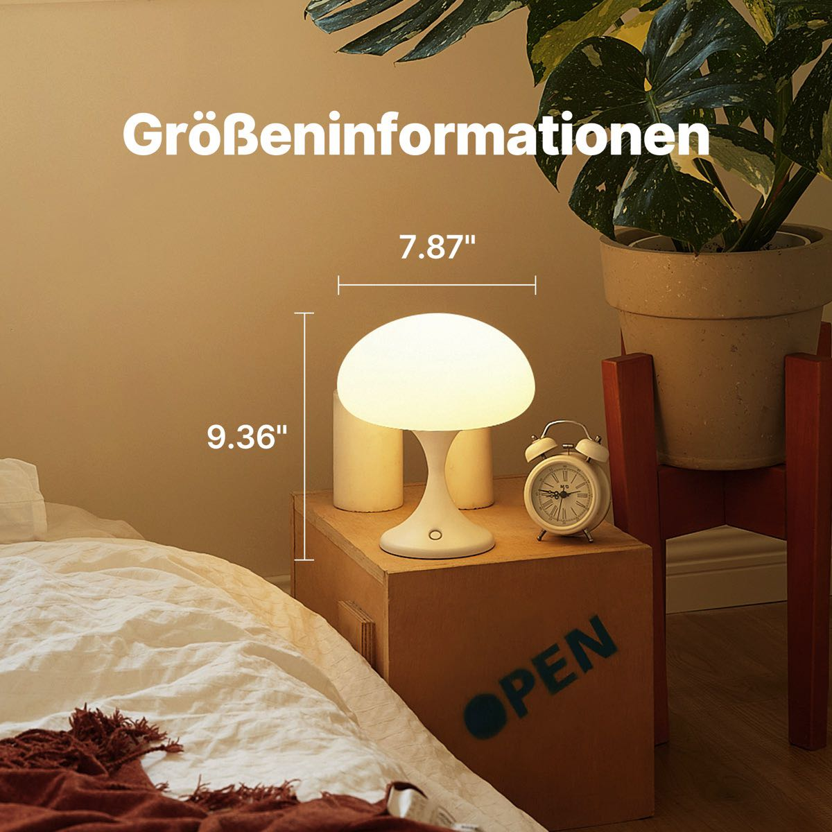 Eine weiße pilzförmige Lampe und eine kleine Uhr auf einer Holzkiste neben einer Pflanze.
