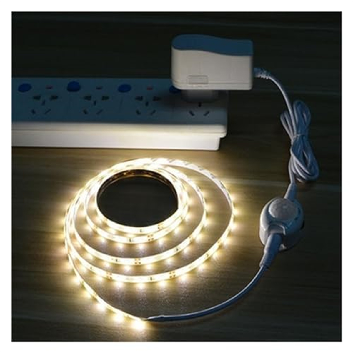Eine Rolle weißer LED-Streifen, aufgerollt mit einer Steckdose. Das Licht ist an.