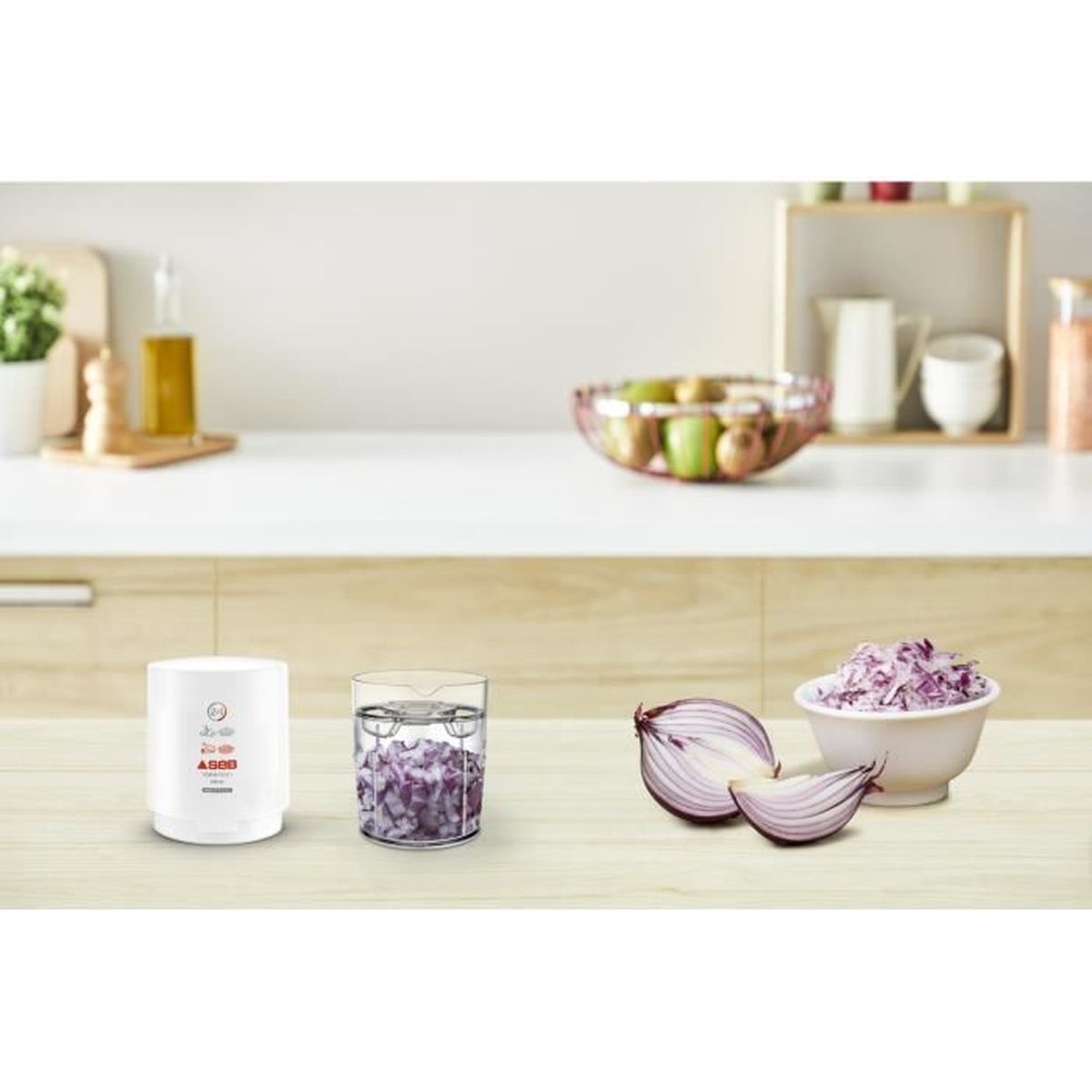 Un robot da cucina bianco, un bicchiere con cipolle rosse tritate, metà cipolle rosse e una ciotola di cavolo tritato.