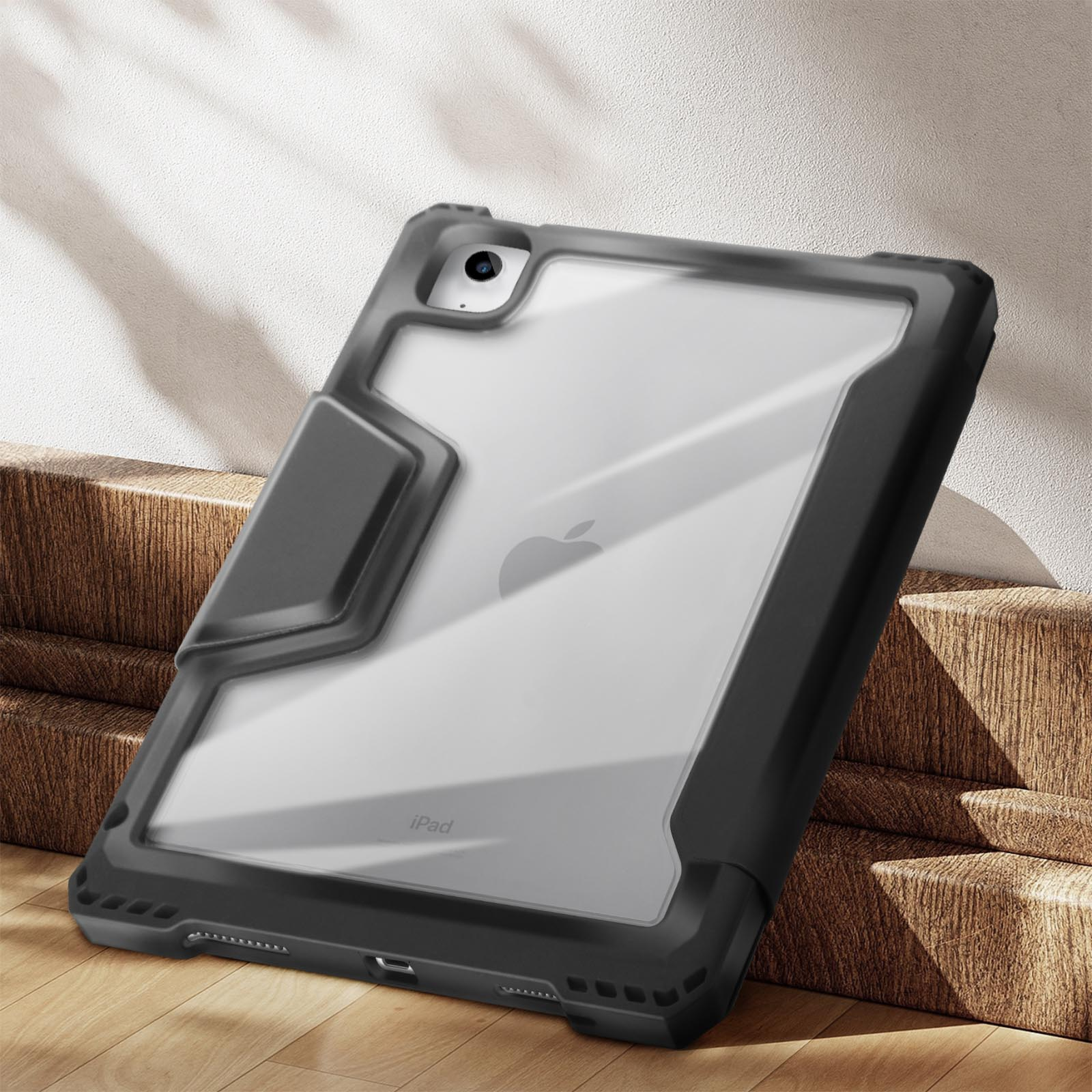 Custodia per tablet nera e trasparente su scale di legno. La custodia ha un retro trasparente e lati neri.