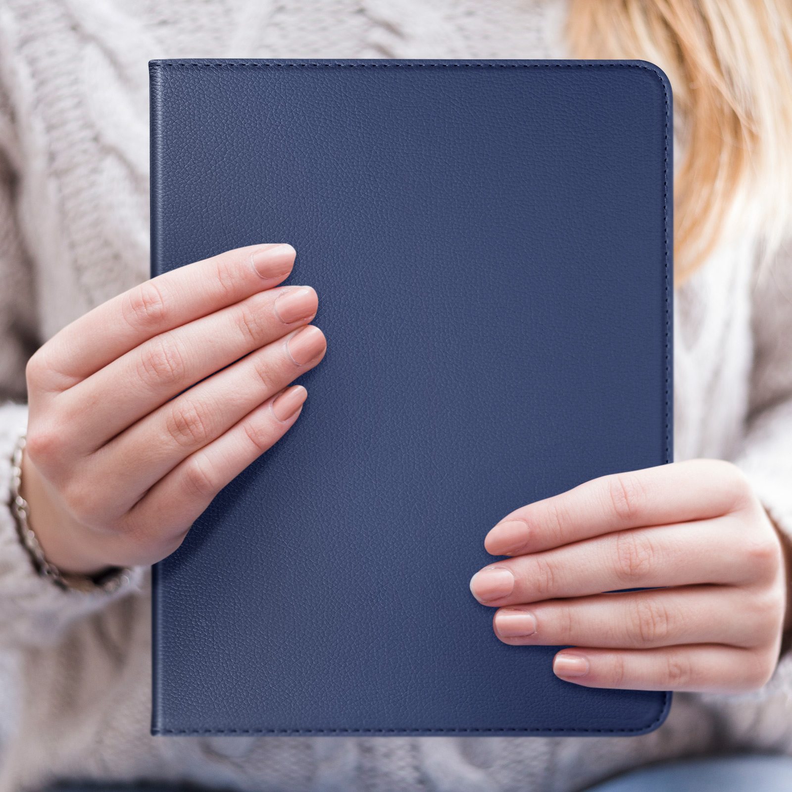 Una donna tiene in mano una custodia blu navy per tablet. Le sue mani sono visibili, custodia chiusa.