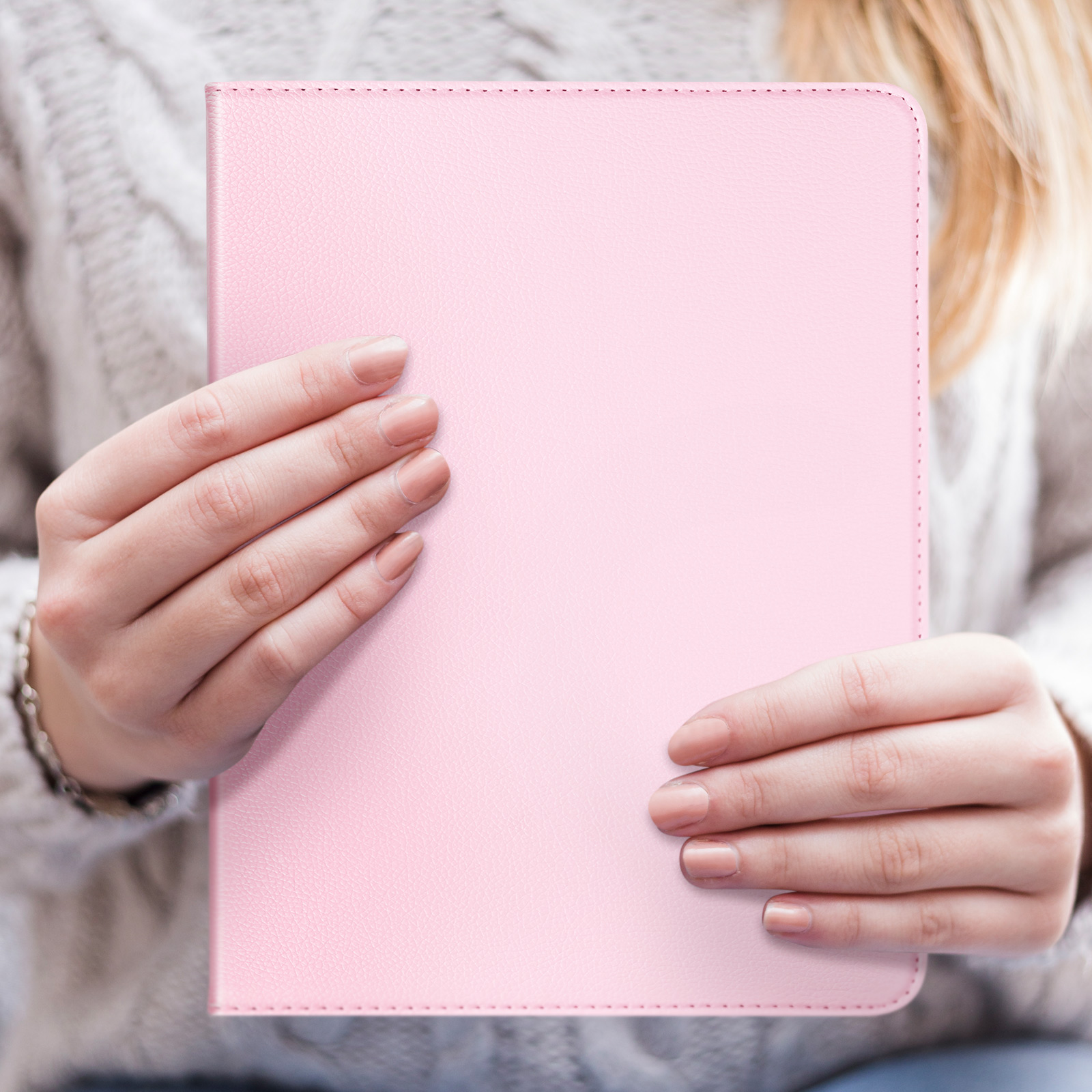 Donna che tiene in mano una custodia rosa per tablet. Maglione beige. Sfondo bianco.