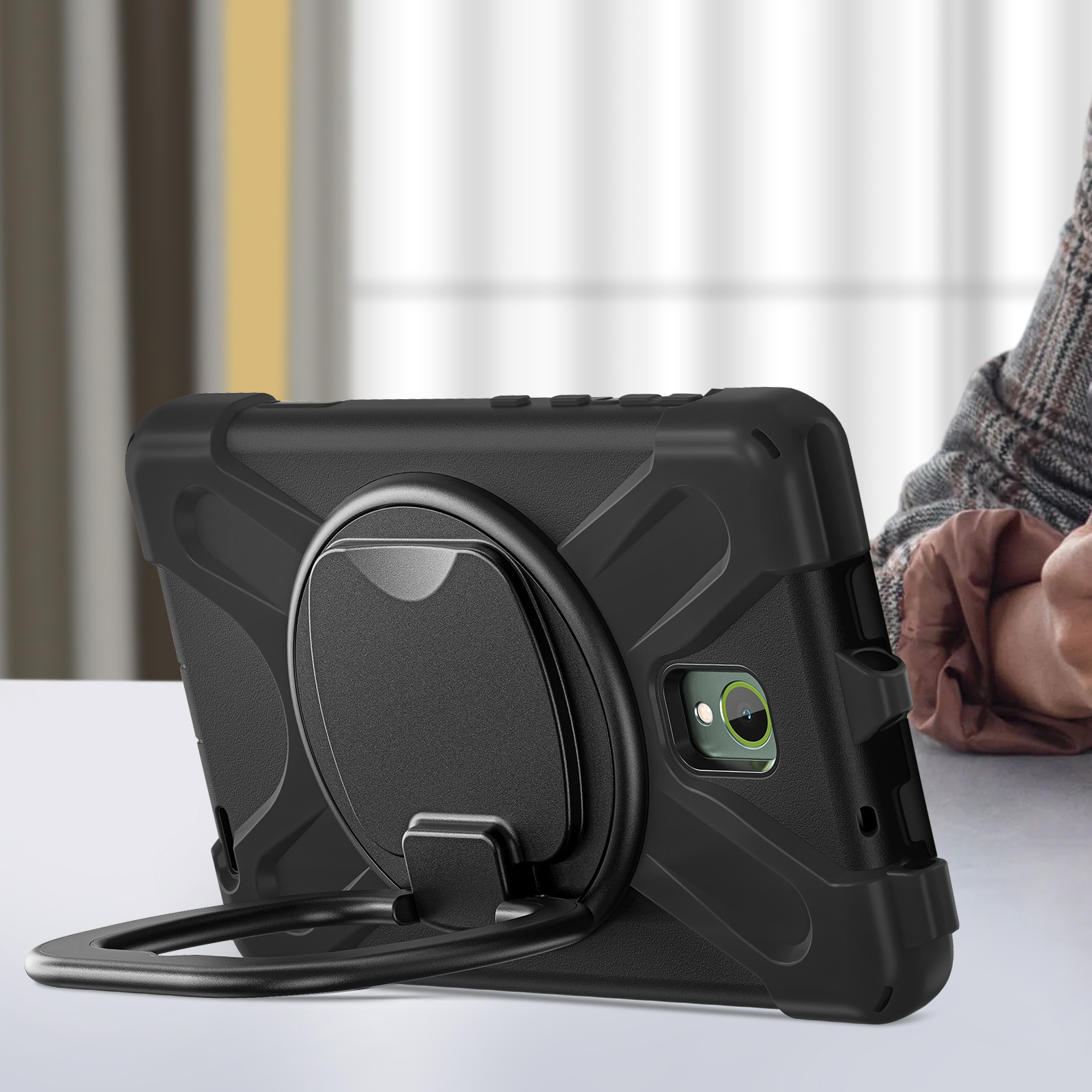 Custodia nera per tablet con supporto ad anello. La mano di una persona è sullo sfondo.