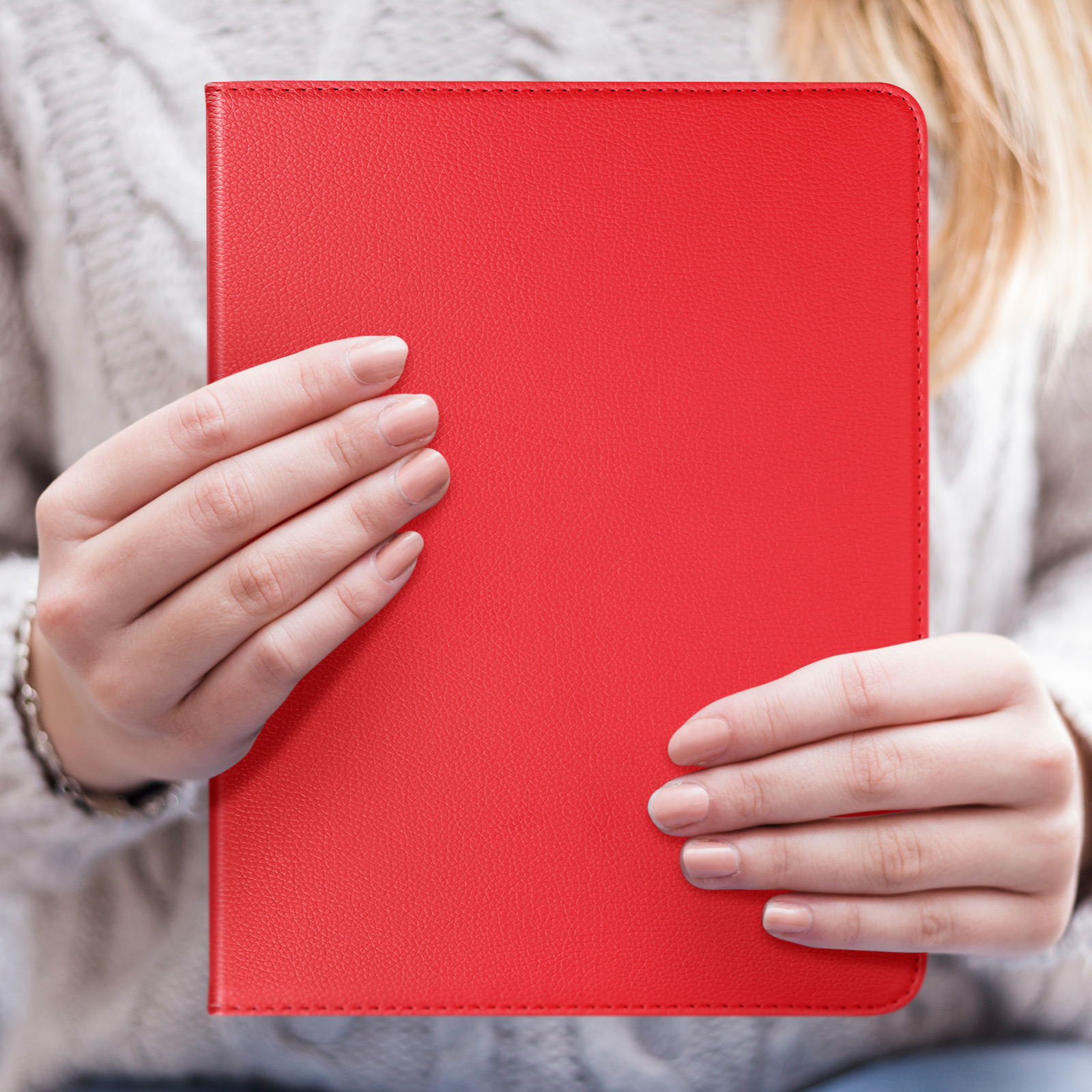 Una persona che tiene una custodia per tablet rossa con entrambe le mani. Sfondo maglione beige.