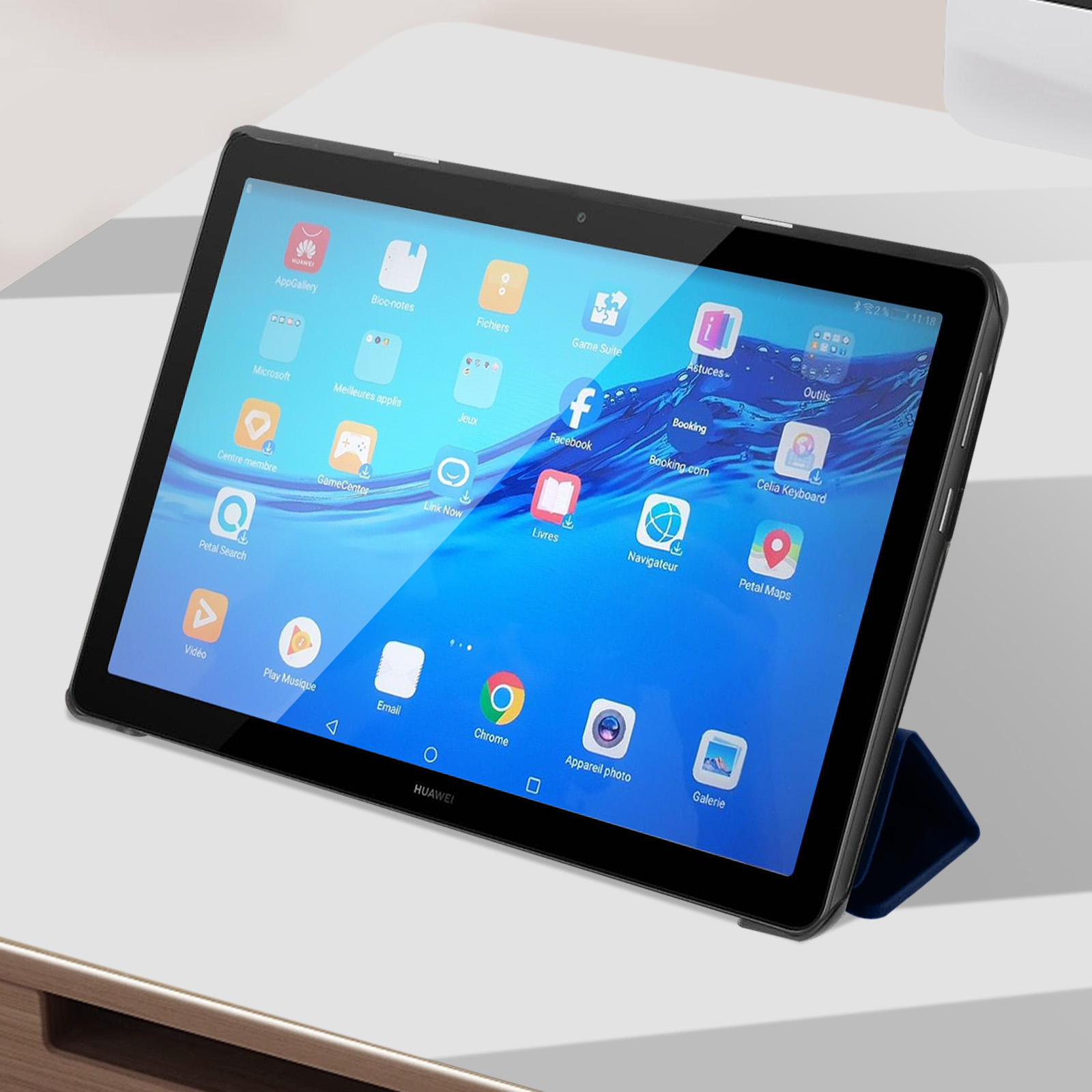 Tablet mit Bildschirm, der Apps anzeigt, gehalten von einem Ständer. Weiße Oberfläche.