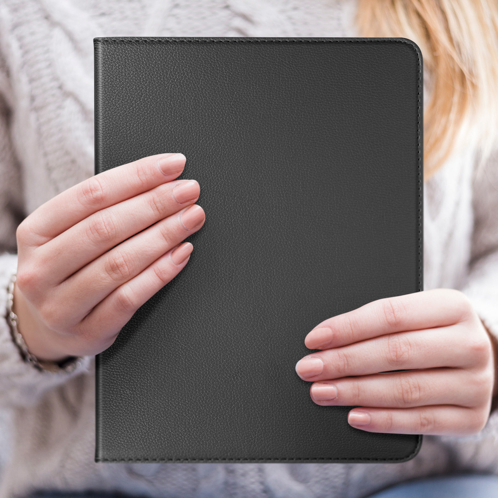 Mani che tengono una custodia per tablet nera. La custodia è chiusa e ha una finitura opaca liscia.