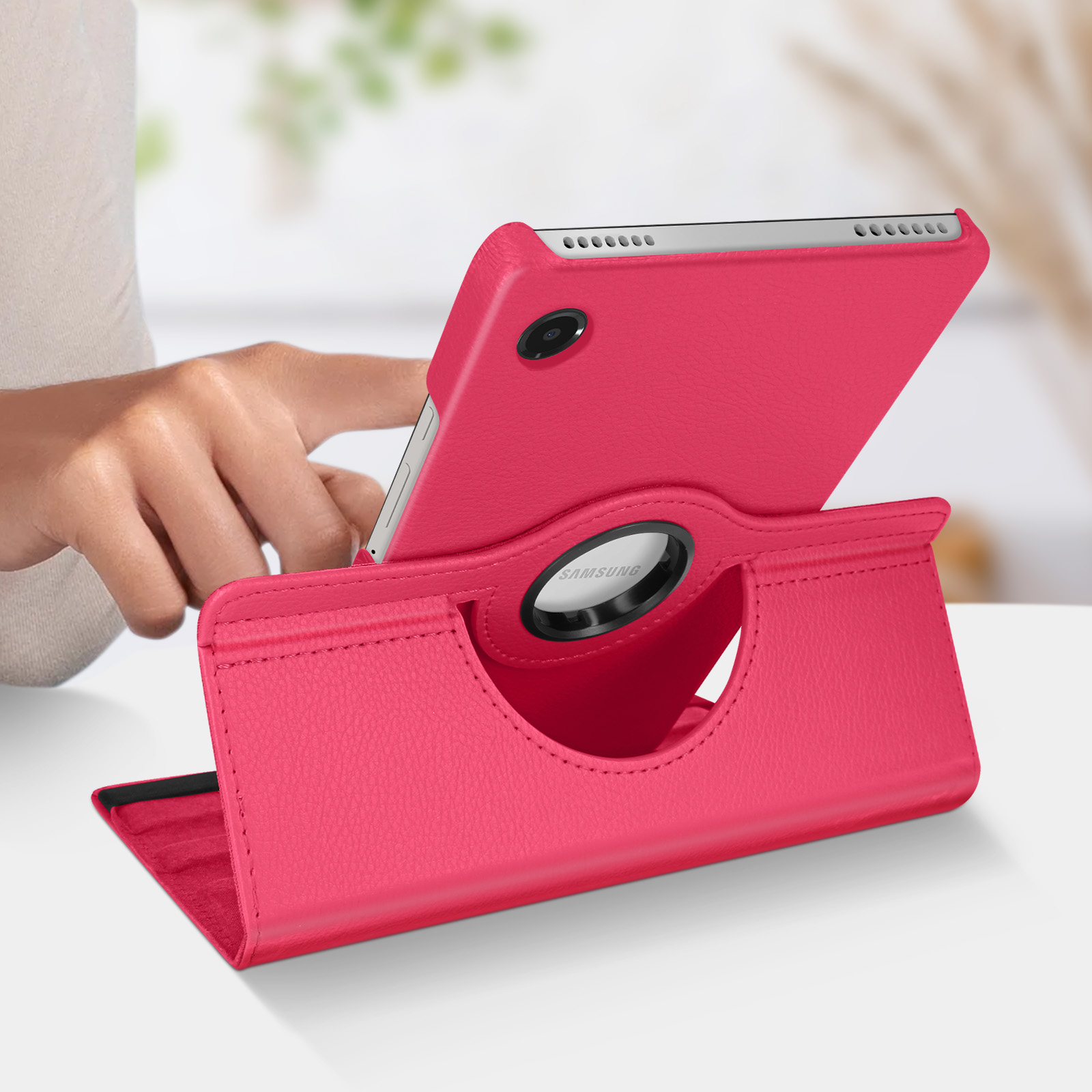 Tablet rosa in un supporto. La mano tocca lo schermo. Sfondo del tavolo bianco.