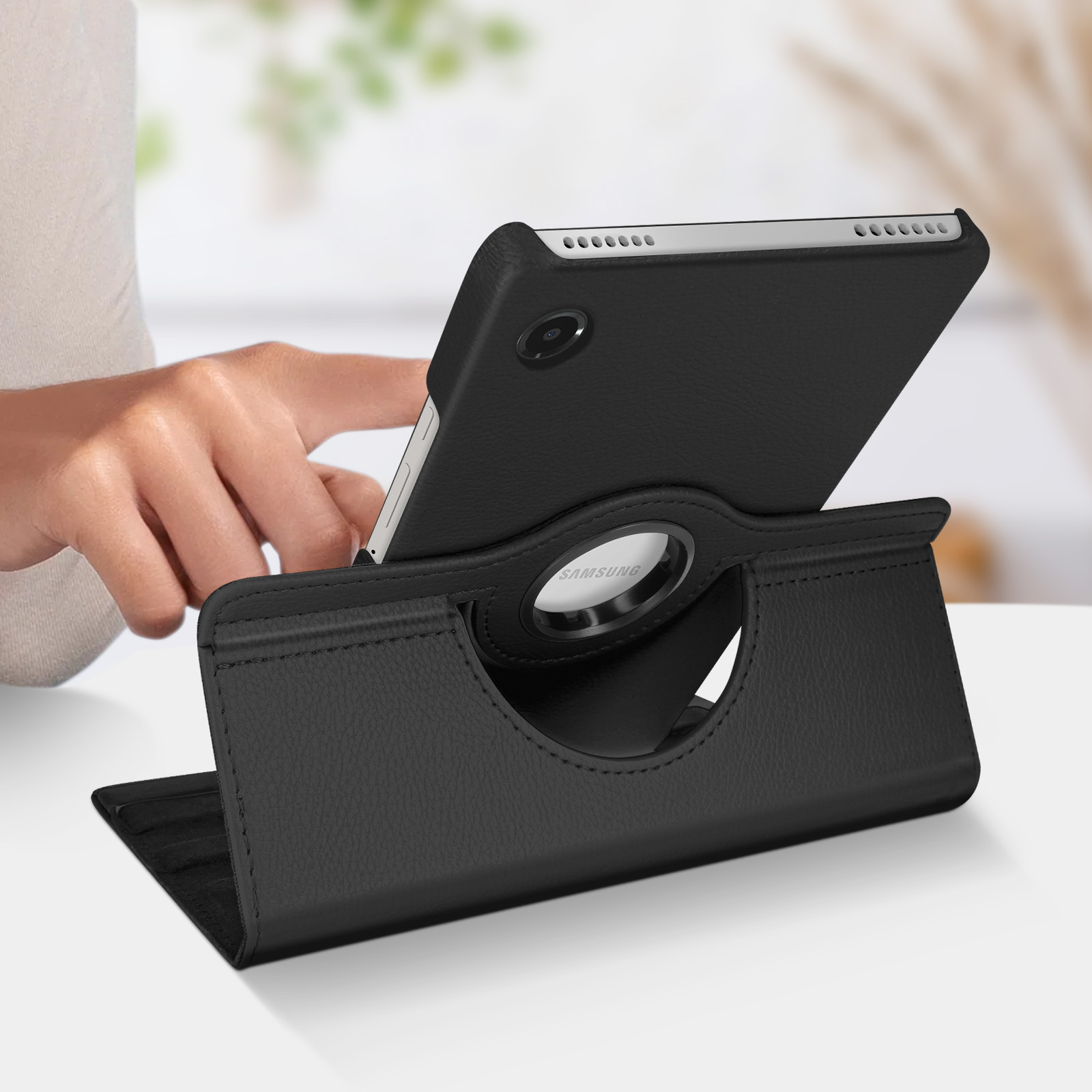 Un tablet in una custodia nera è appoggiato per la visualizzazione. Una mano è visibile.
