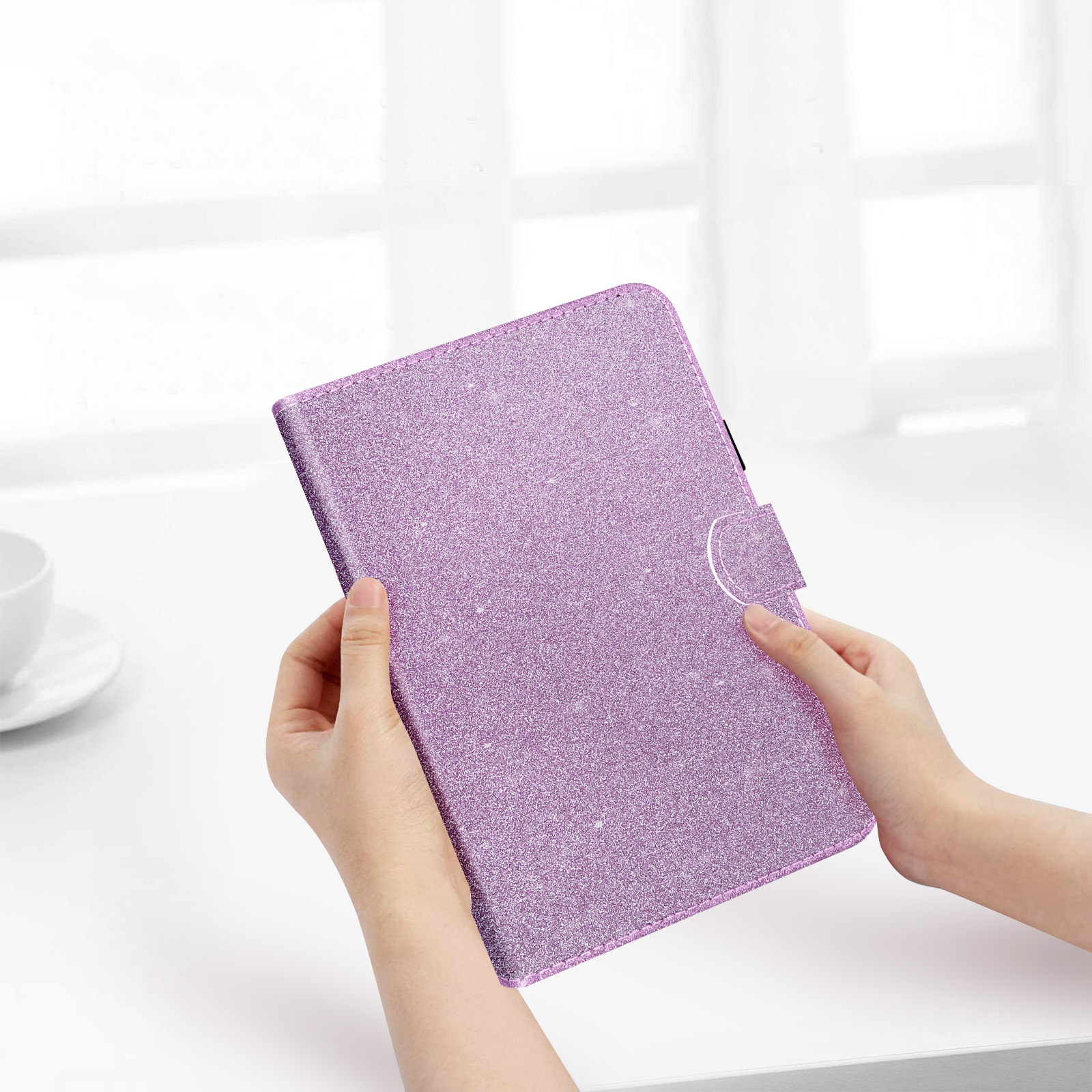 Mani che tengono una custodia per tablet glitterata viola. La custodia è chiusa con un fermaglio.