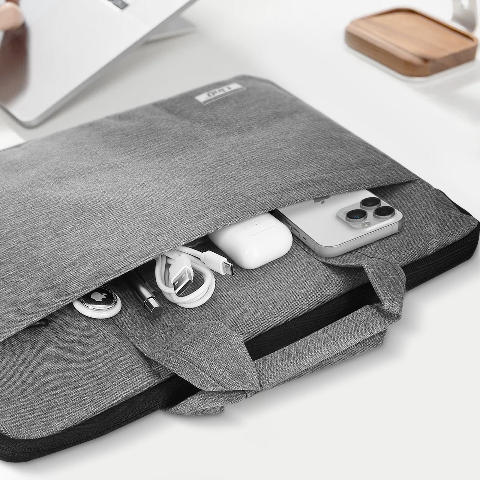 Eine graue Laptoptasche mit verschiedenen Gegenständen, darunter ein Telefon und Kabel.