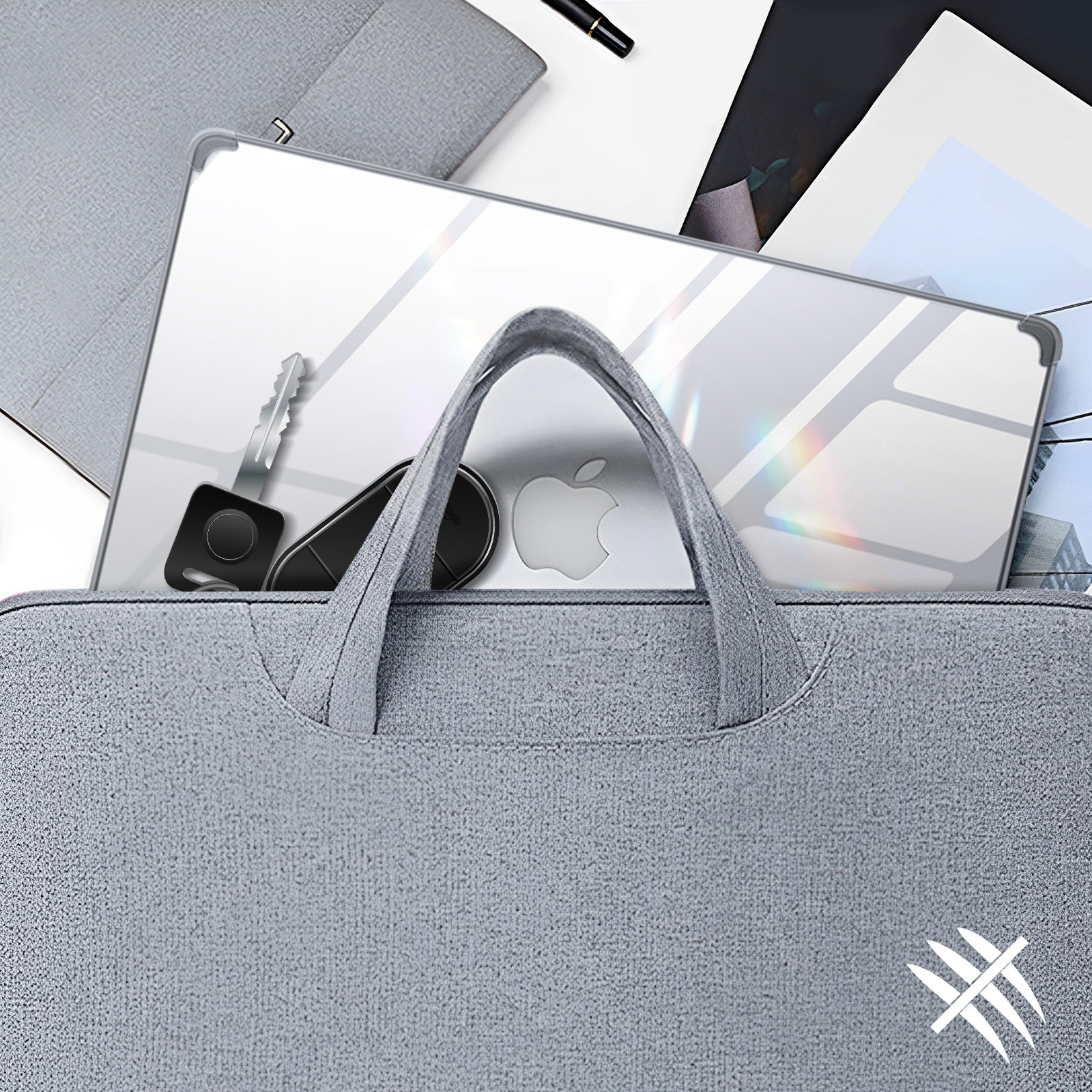 Laptop e accessori in una borsa grigia. Chiavi e penna sul tavolo.