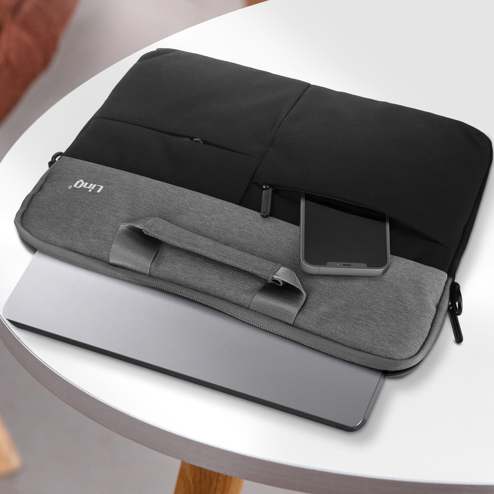 Ordinateur portable et téléphone dans un sac d'ordinateur portable gris sur une table blanche. Sac noir.