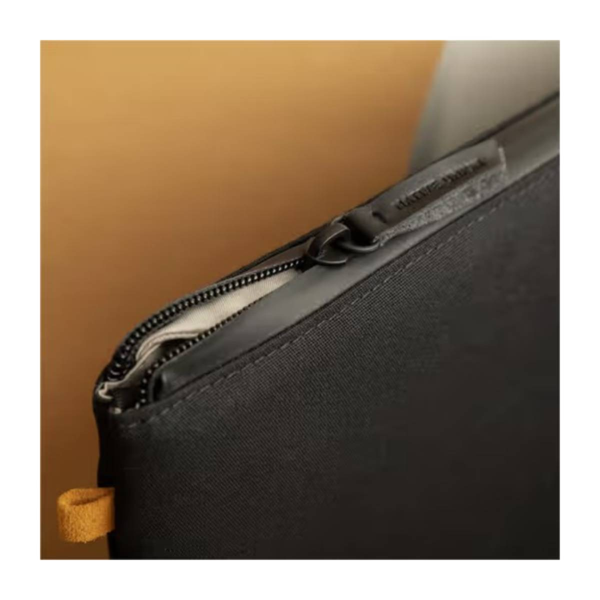 Gros plan d'un sac noir zippé, avec une étiquette jaune attachée.