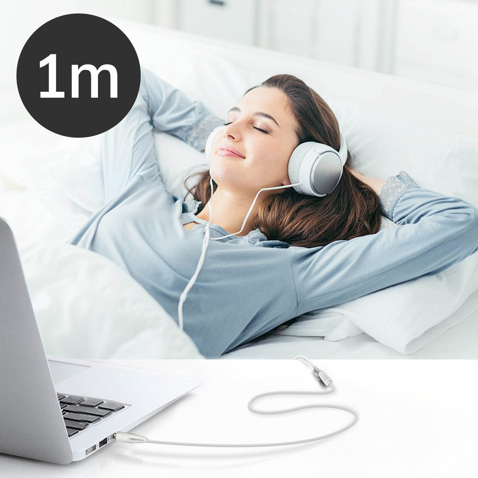Una donna a letto con le cuffie, collegata a un laptop con un cavo bianco da 1 m.