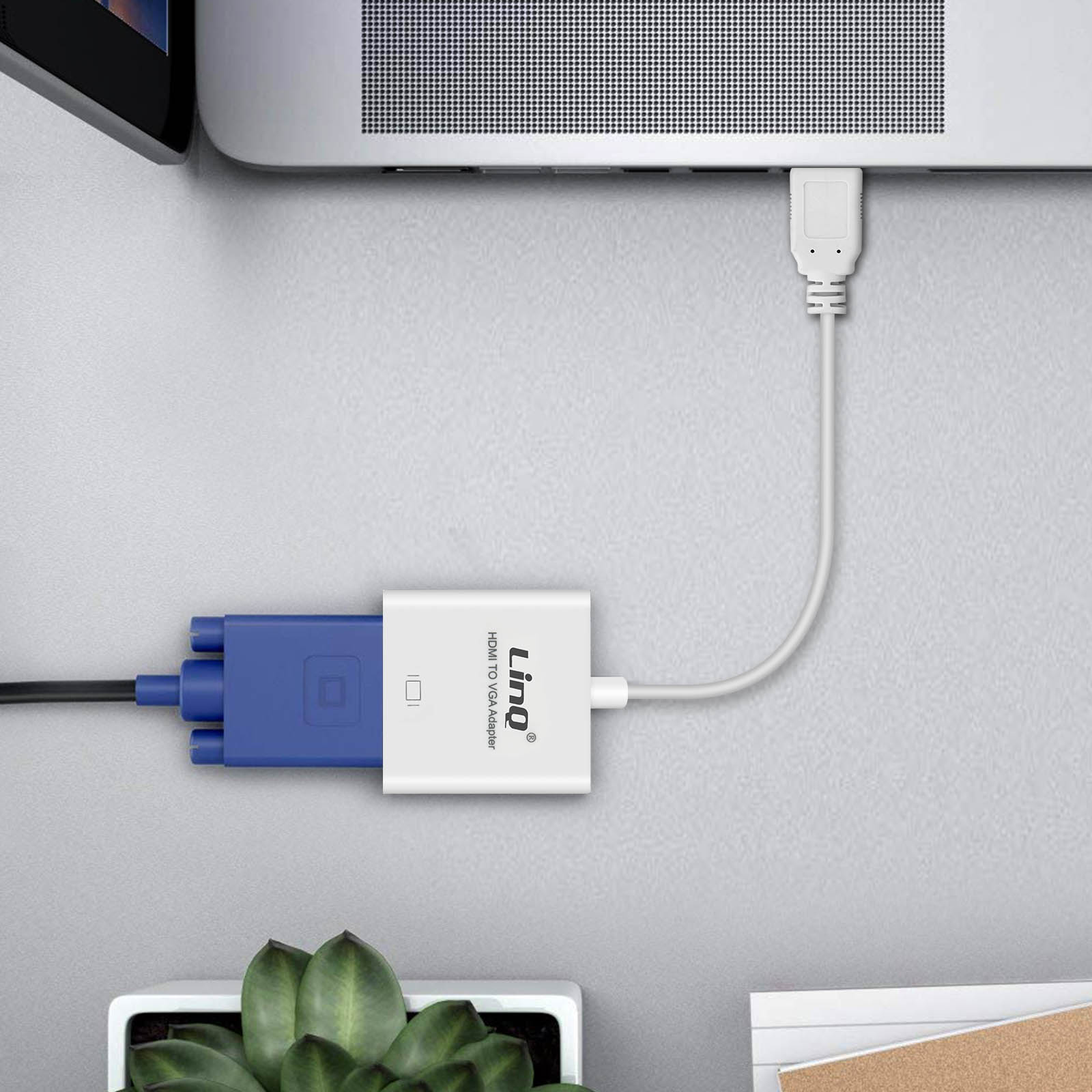 Un adattatore da HDMI a VGA collegato a un laptop e un cavo VGA, su una superficie grigia.
