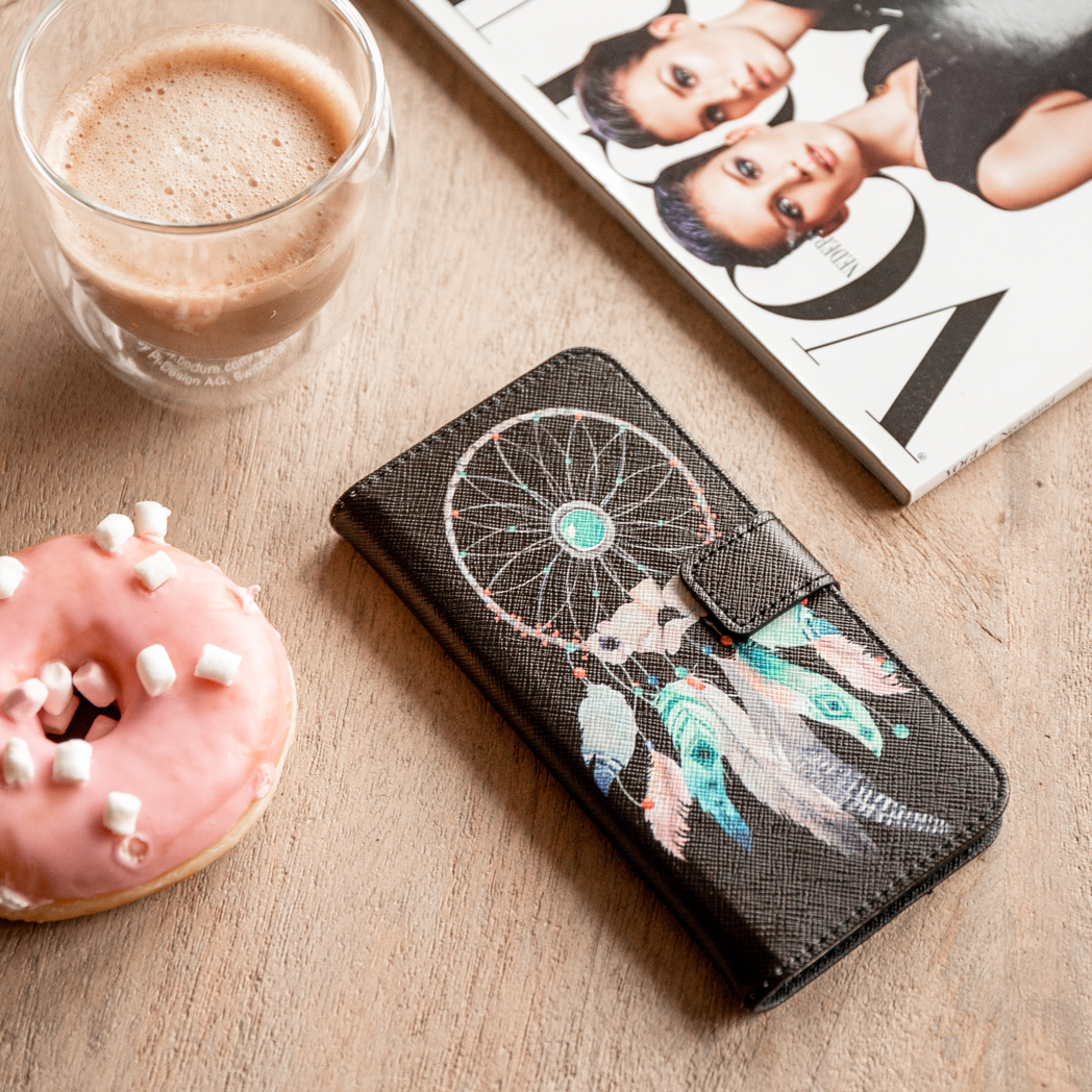 Donut et tasse de café. Un étui de téléphone avec un motif attrape-rêves ouvert à côté d'un magazine.