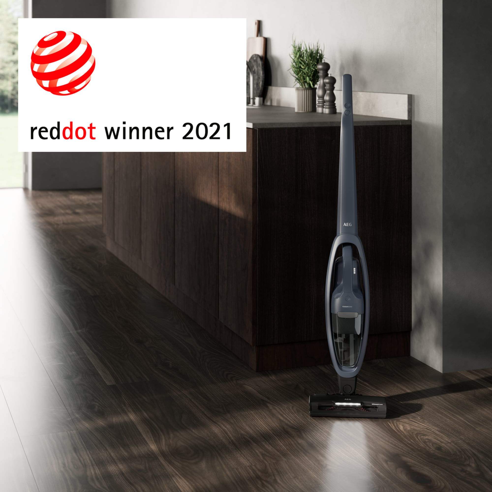 Una aspiradora inalámbrica en un piso de madera con Red Dot Winner 2021 y un mueble de cocina.
