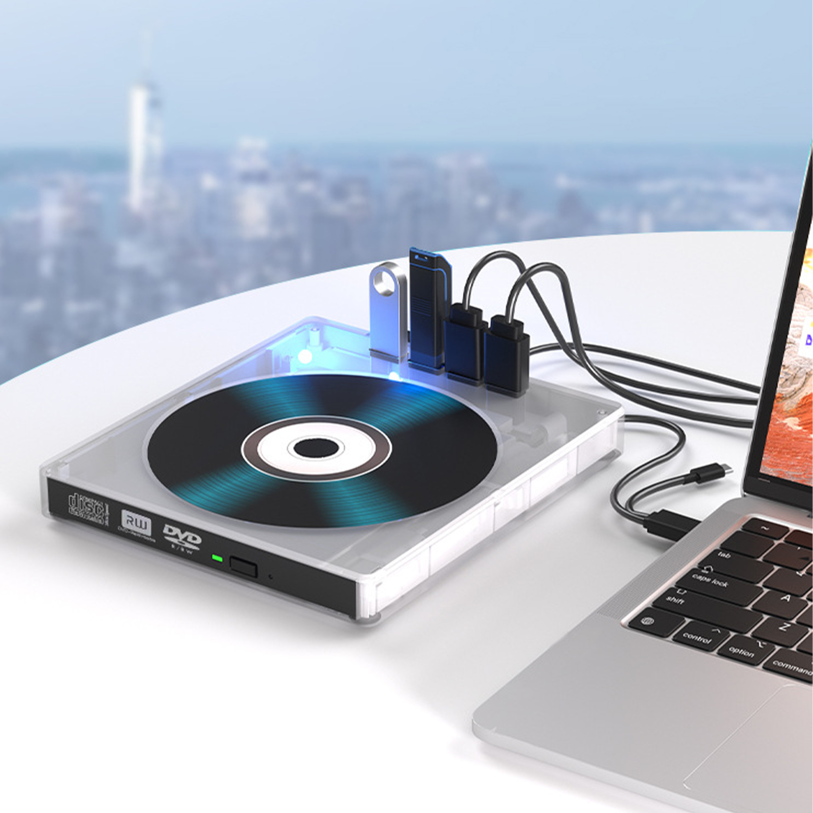 DVD-Laufwerk mit USB-Anschlüssen, verbunden mit einem Laptop, auf einem weißen Tisch. Stadtkulisse.