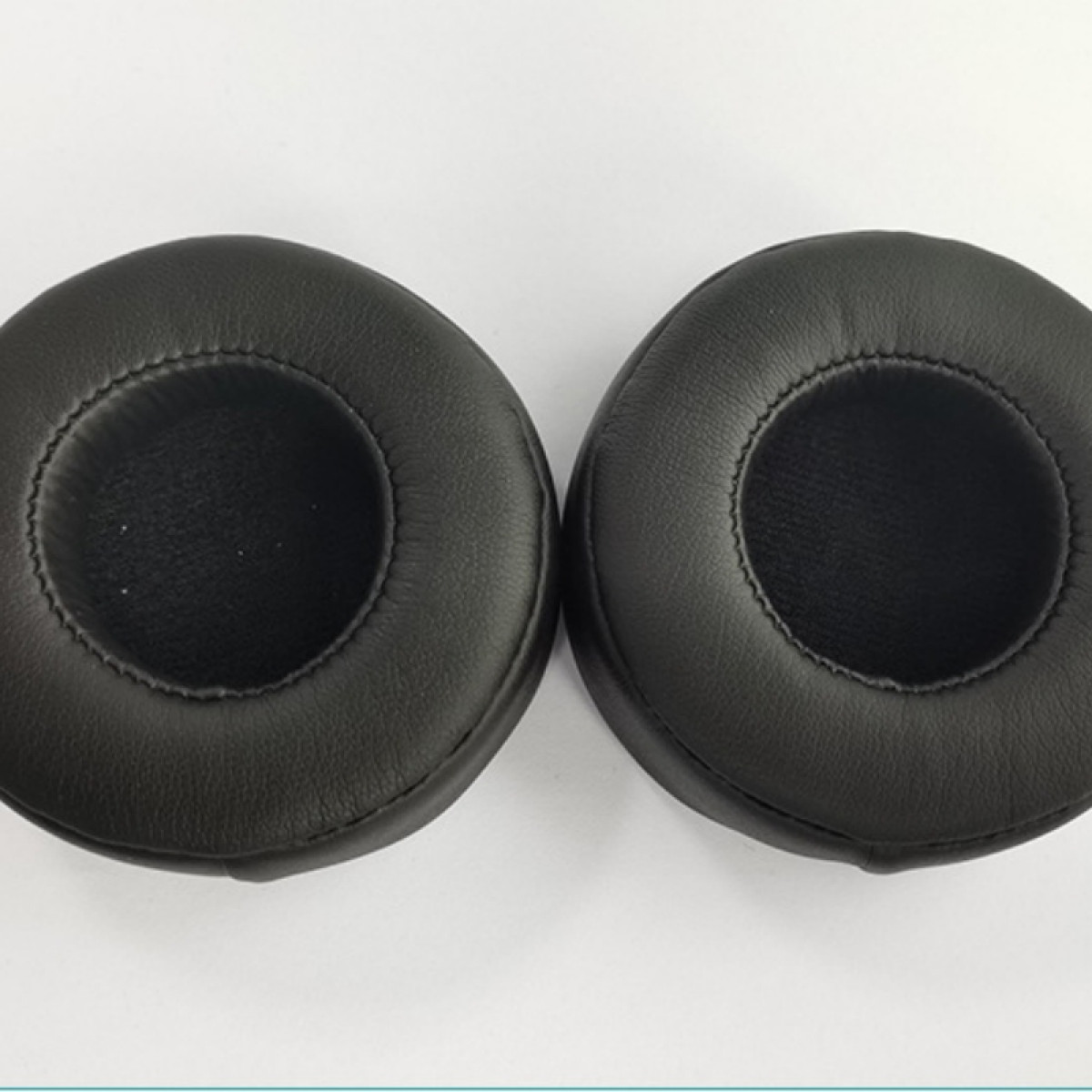 Due cuscinetti auricolari neri per cuffie, forma circolare.