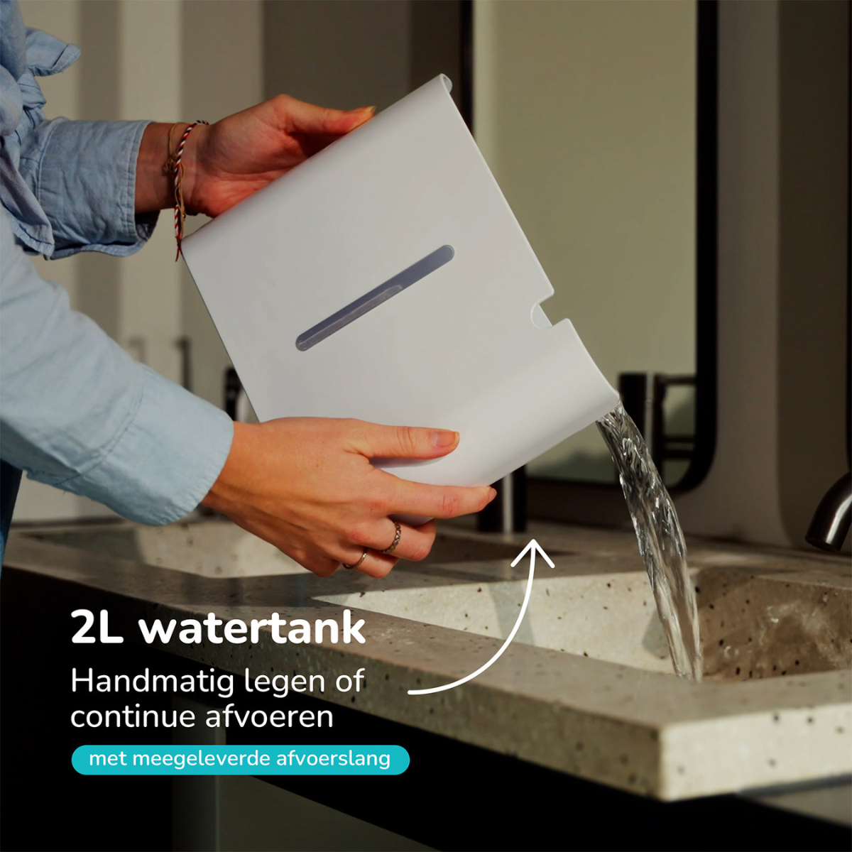 Eine Person gießt Wasser aus einem weißen Tank in ein Waschbecken. Text zeigt 2L Kapazität und Entleerungsanweisungen.