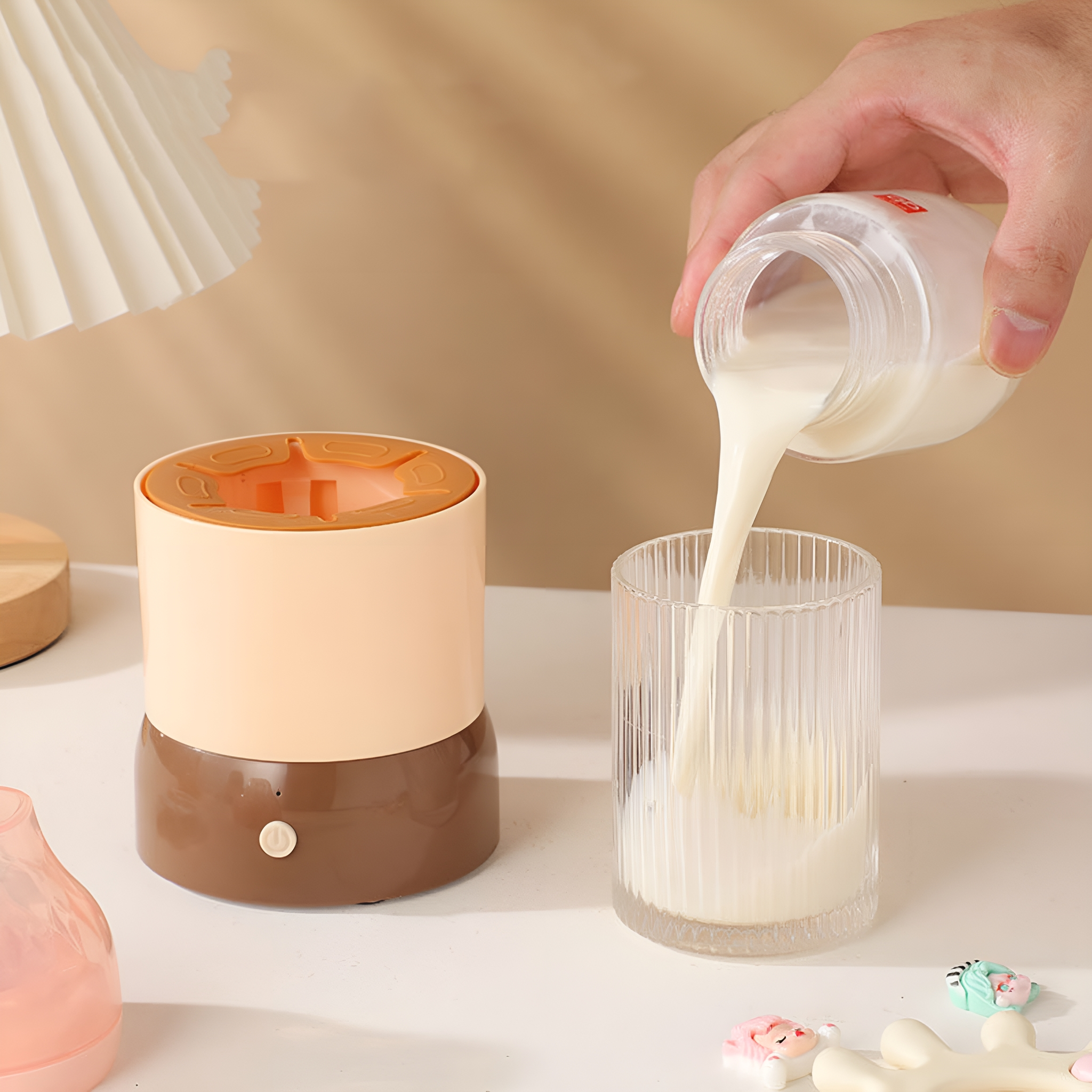 Eine Hand gießt Milch aus einer Flasche in ein Glas neben einem Wärmer.