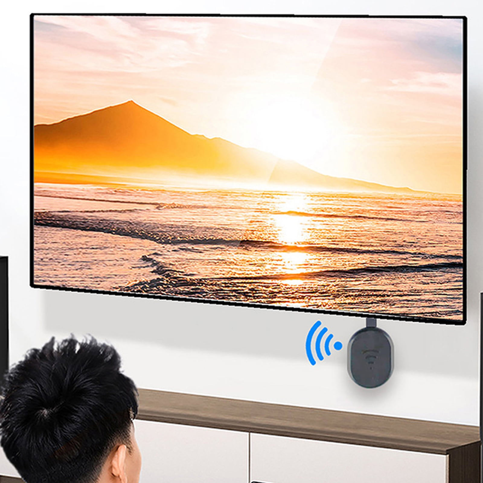 Ein Mann betrachtet einen Fernsehbildschirm mit einem Sonnenuntergang über dem Meer, verbunden mit einem schwarzen Streaming-Gerät.