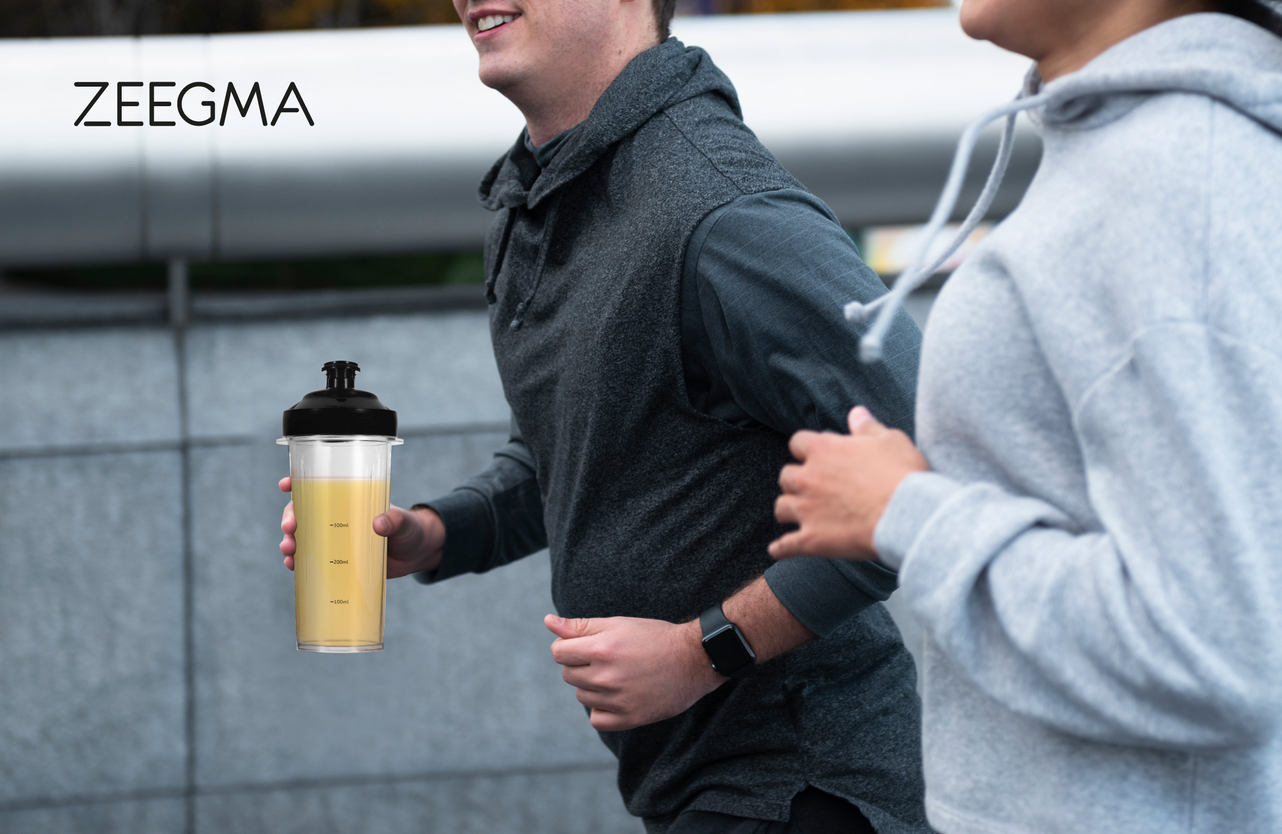 Dwie osoby biegną. Jedna trzyma przezroczystą butelkę z żółtym płynem.