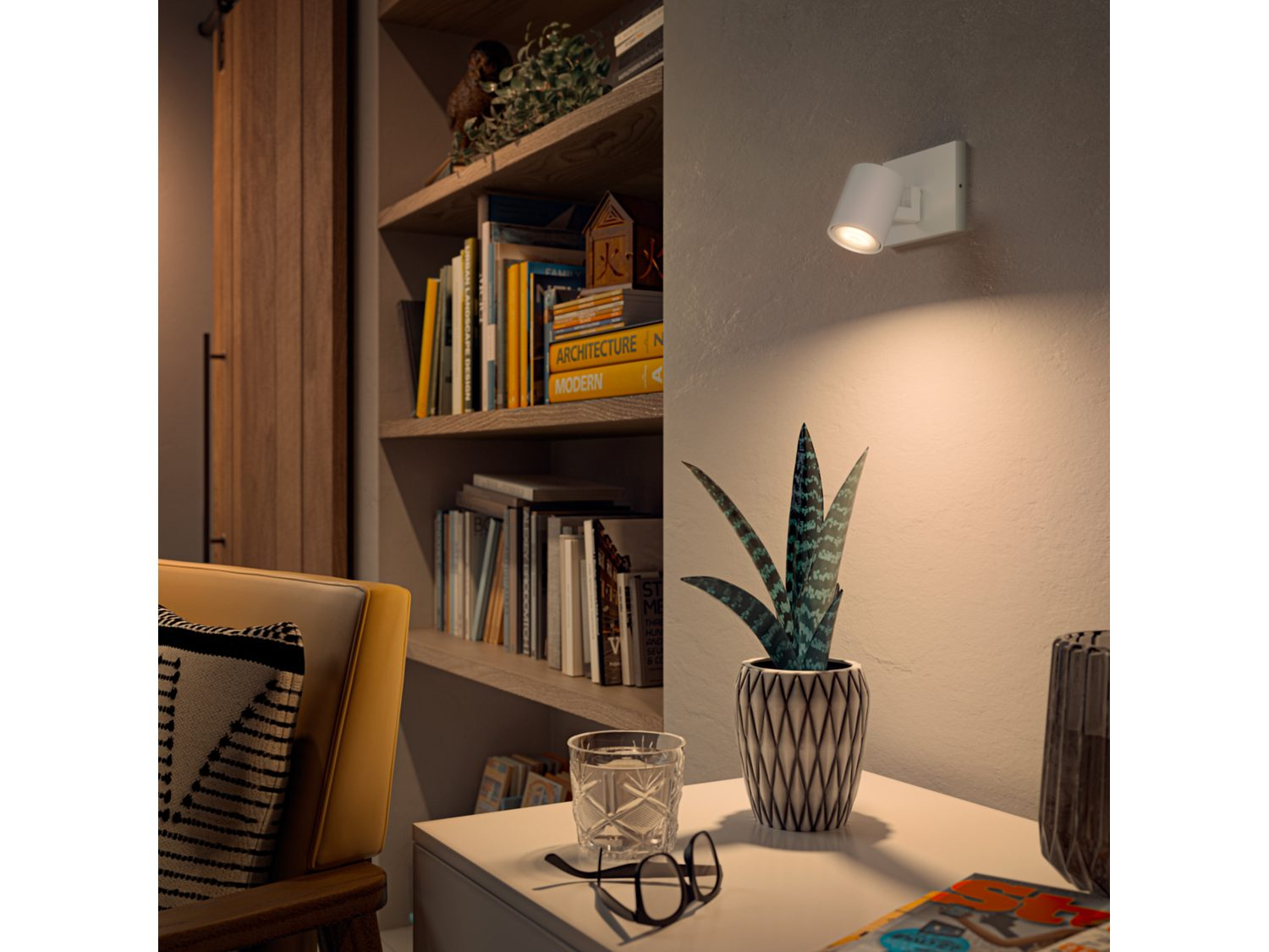 Een verlichte kamer met een boekenplank en een plant. Een spot schijnt op de muur.