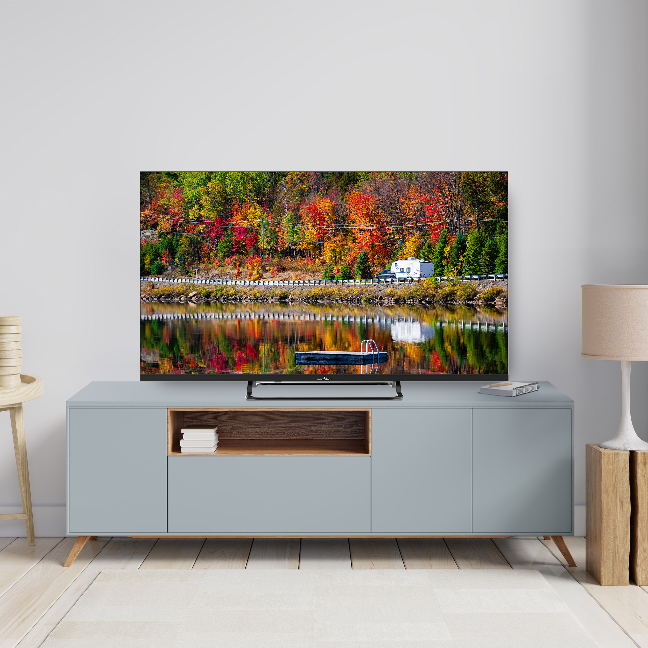 Ekran telewizora wyświetlający kolorowy jesienny krajobraz odbity w wodzie, w pokoju.