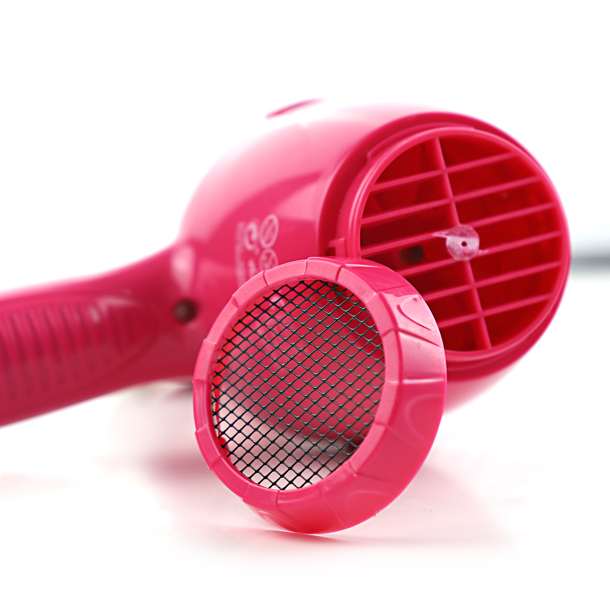 Różowa suszarka do włosów z otwartym filtrem powietrza. Białe tło.
