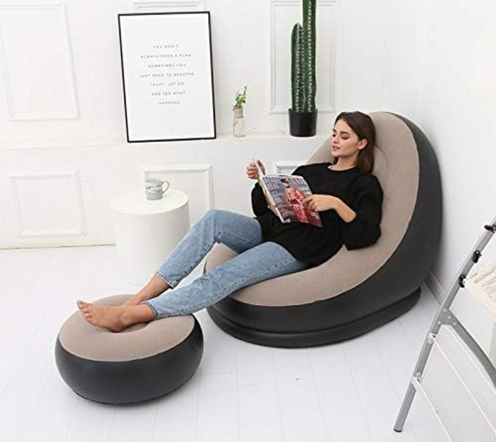 Una mujer lee en una silla inflable con reposapiés. Un cuadro enmarcado y un cactus en el fondo.