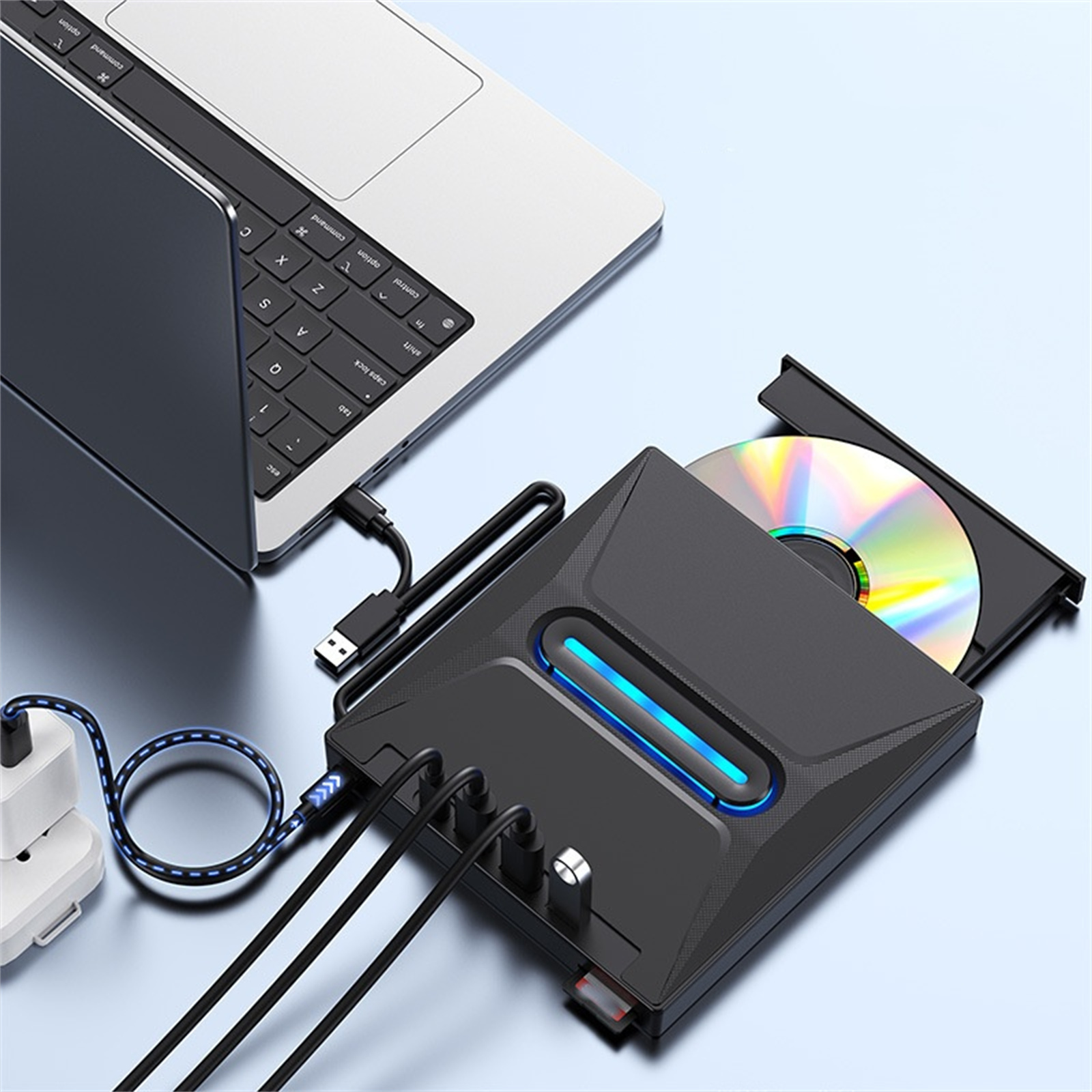 Schwarzes externes CD/DVD-Laufwerk, das an einen Laptop angeschlossen ist, mit USB- und Stromkabeln. Eine CD ist im Laufwerk.