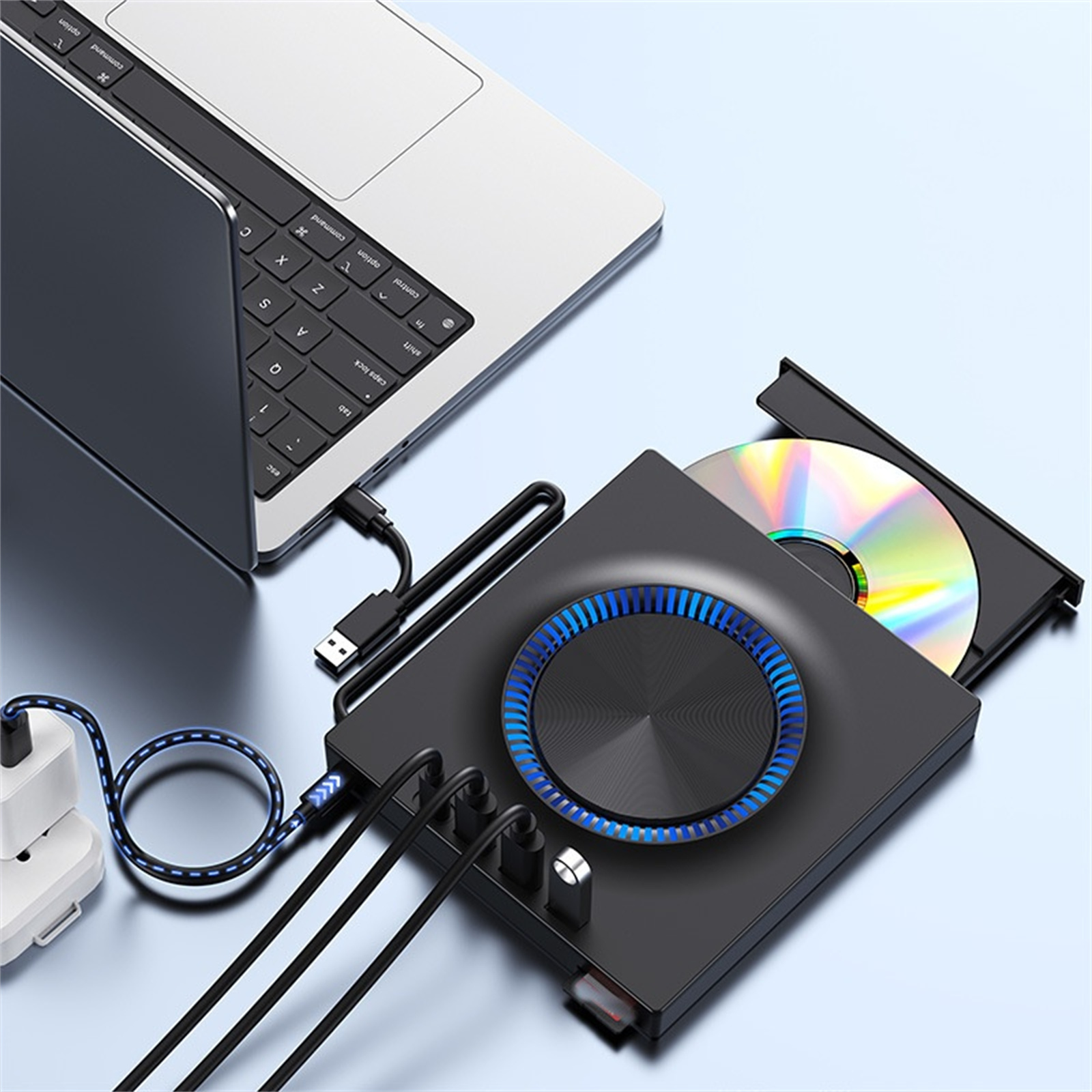 Ein Laptop, der mit einem schwarzen Gerät mit CD und verschiedenen Kabeln verbunden ist.