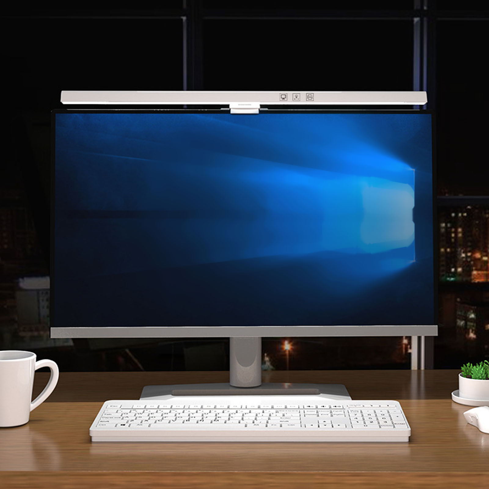 Ein Computermonitor mit einem Lichtbalken oben, eine weiße Tastatur und eine weiße Kaffeetasse auf einem Holzschreibtisch.