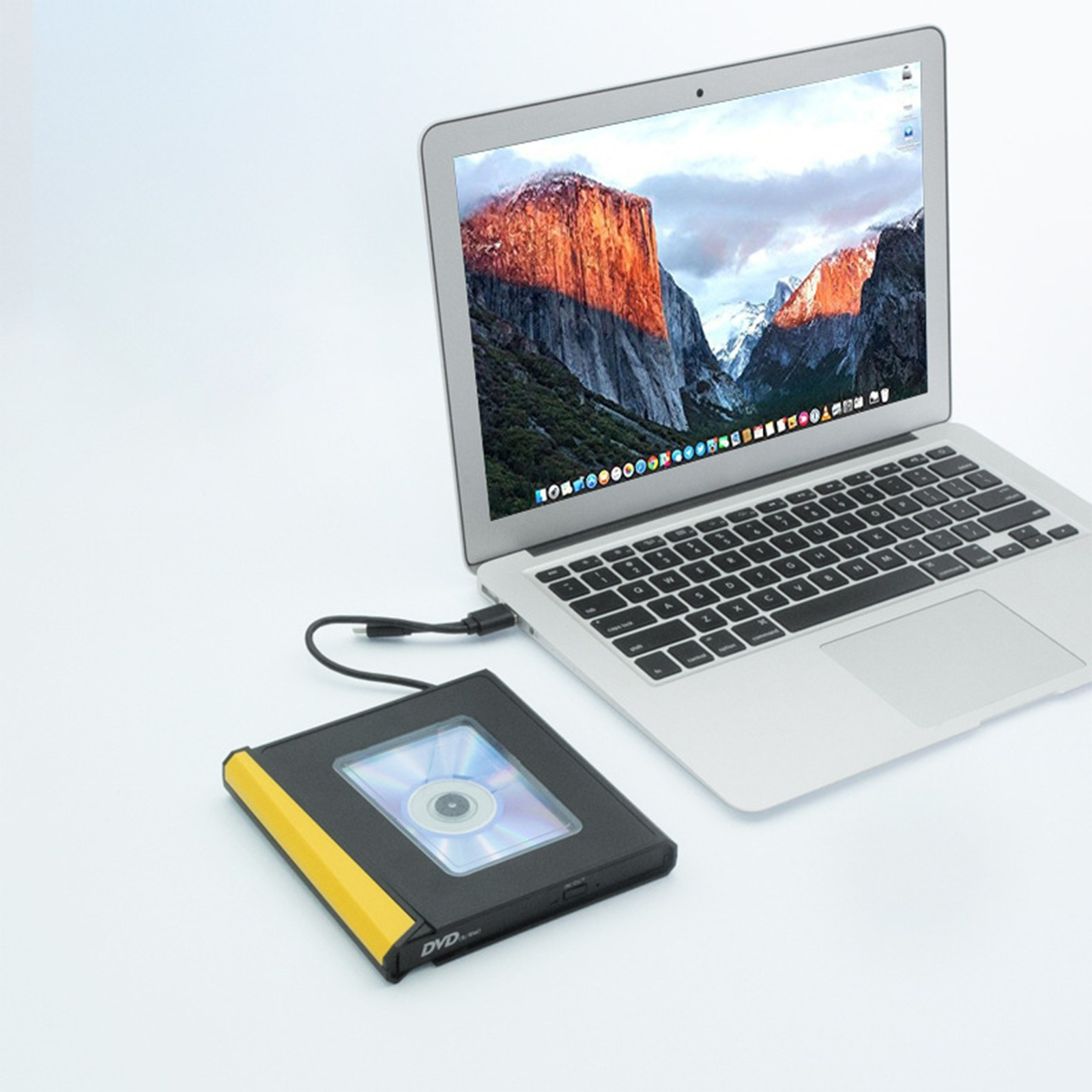 Laptop mit angeschlossenem DVD-Laufwerk. Das DVD-Laufwerk ist schwarz und gelb, mit eingelegter Disc.