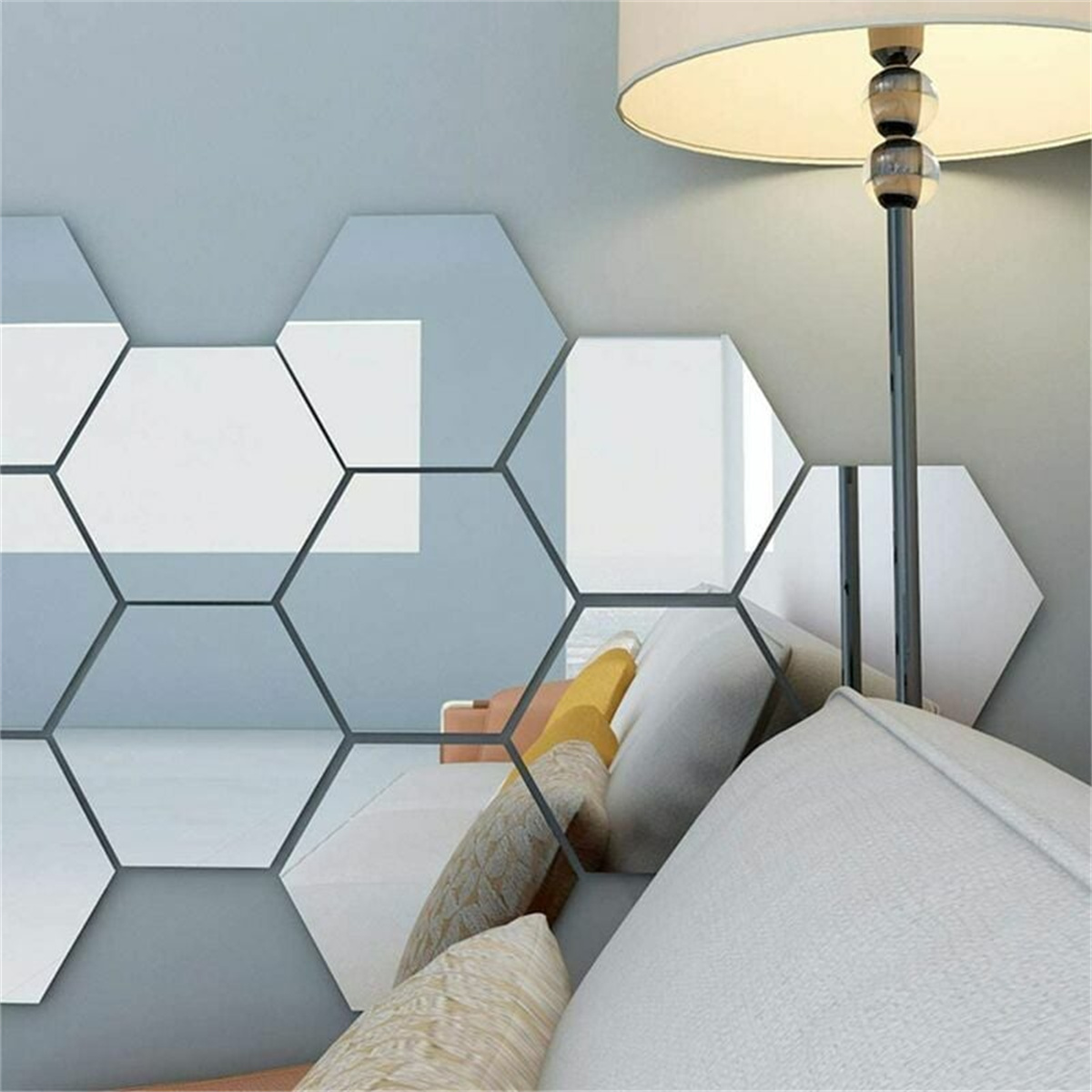 Hellblaue Wand mit sechseckigen Spiegeln und Sofa mit Kissen.