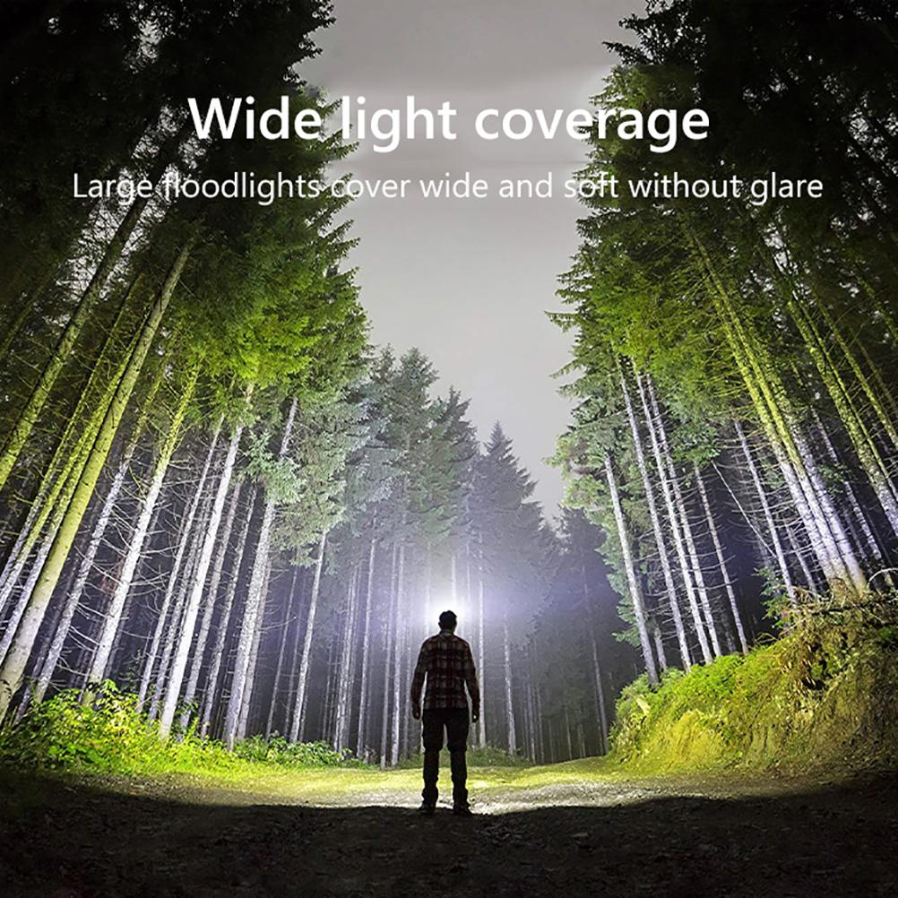 Mann in einem Wald, ein Licht scheint auf ihn. Die Bäume sind hoch und der Himmel ist hell.