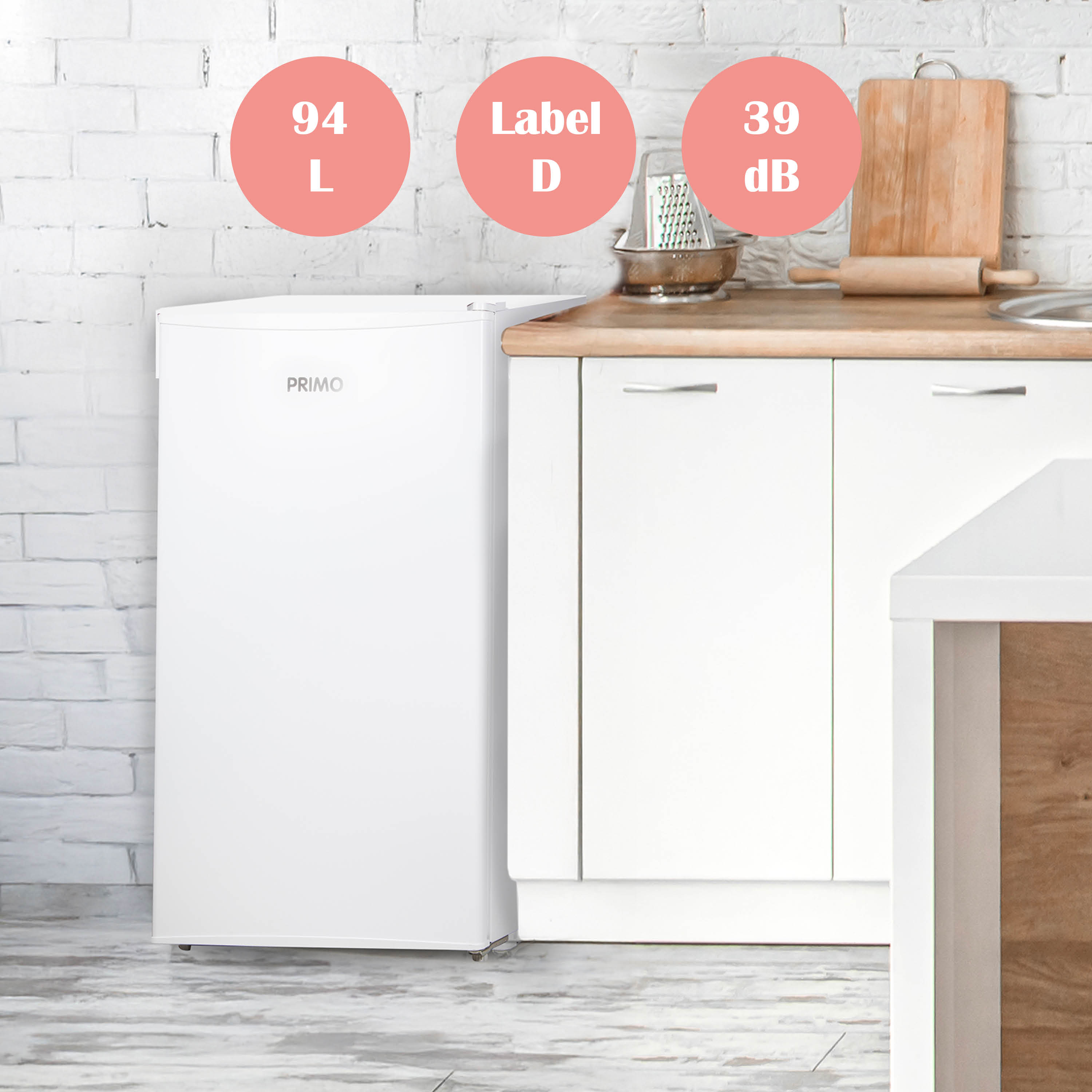 Witte Primo-koelkast in een keuken. Labels van 94L, Label D en 39dB staan in roze cirkels.