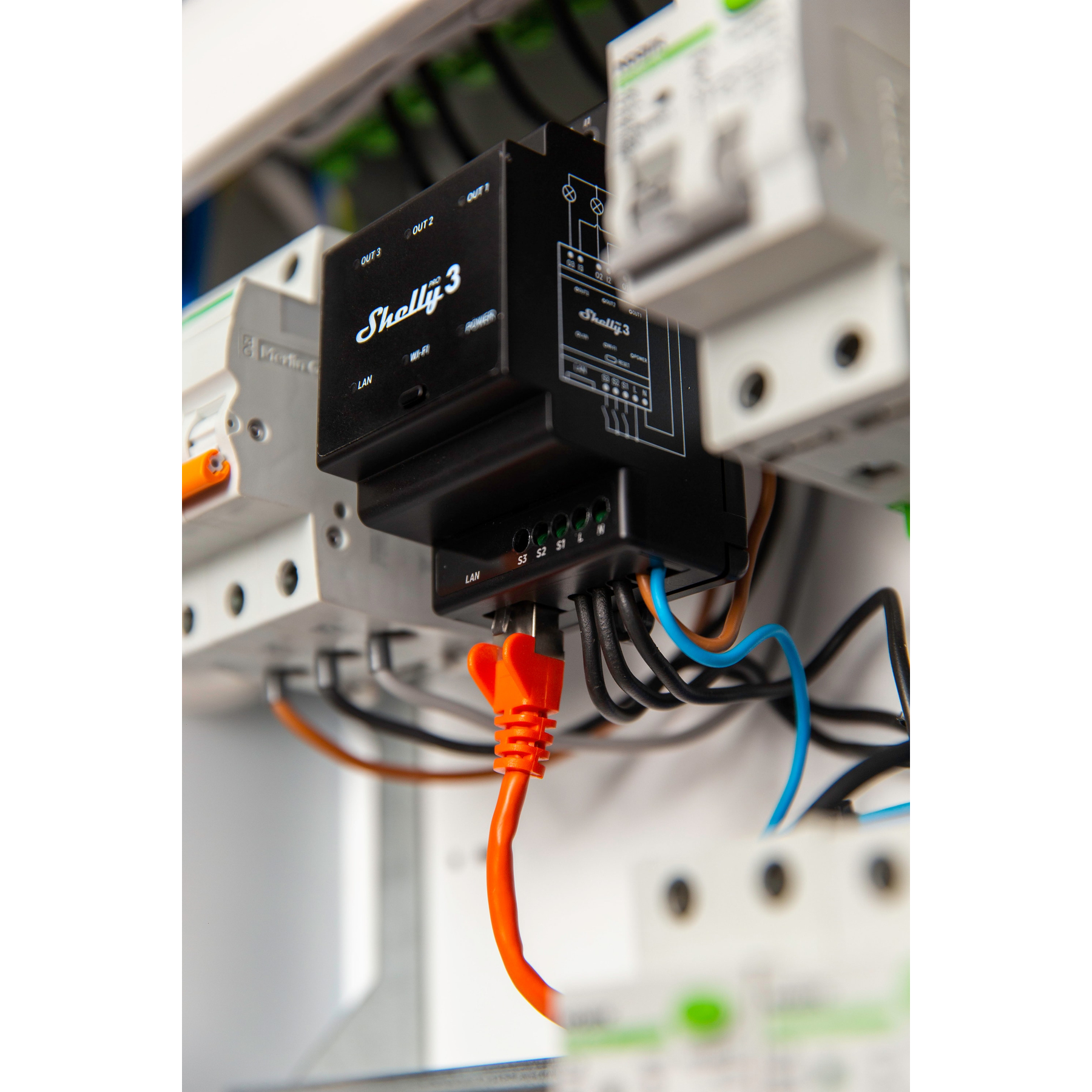 Elementy elektryczne, w tym urządzenie smart home, pomarańczowy kabel.