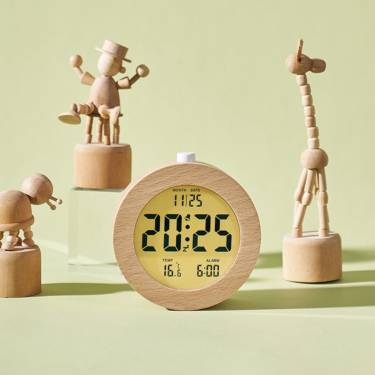 Holzuhr und Figuren von Tieren, Holzgiraffe und Mann, auf einem Tisch.