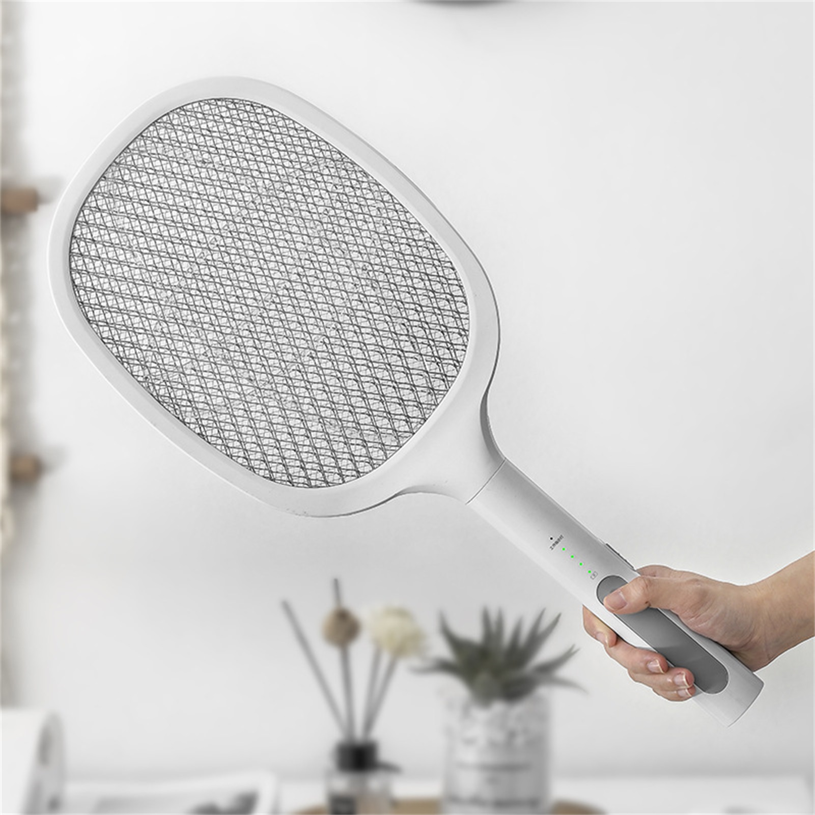 Elektrischer Fliegenfänger, weiß, von einer Hand gehalten.