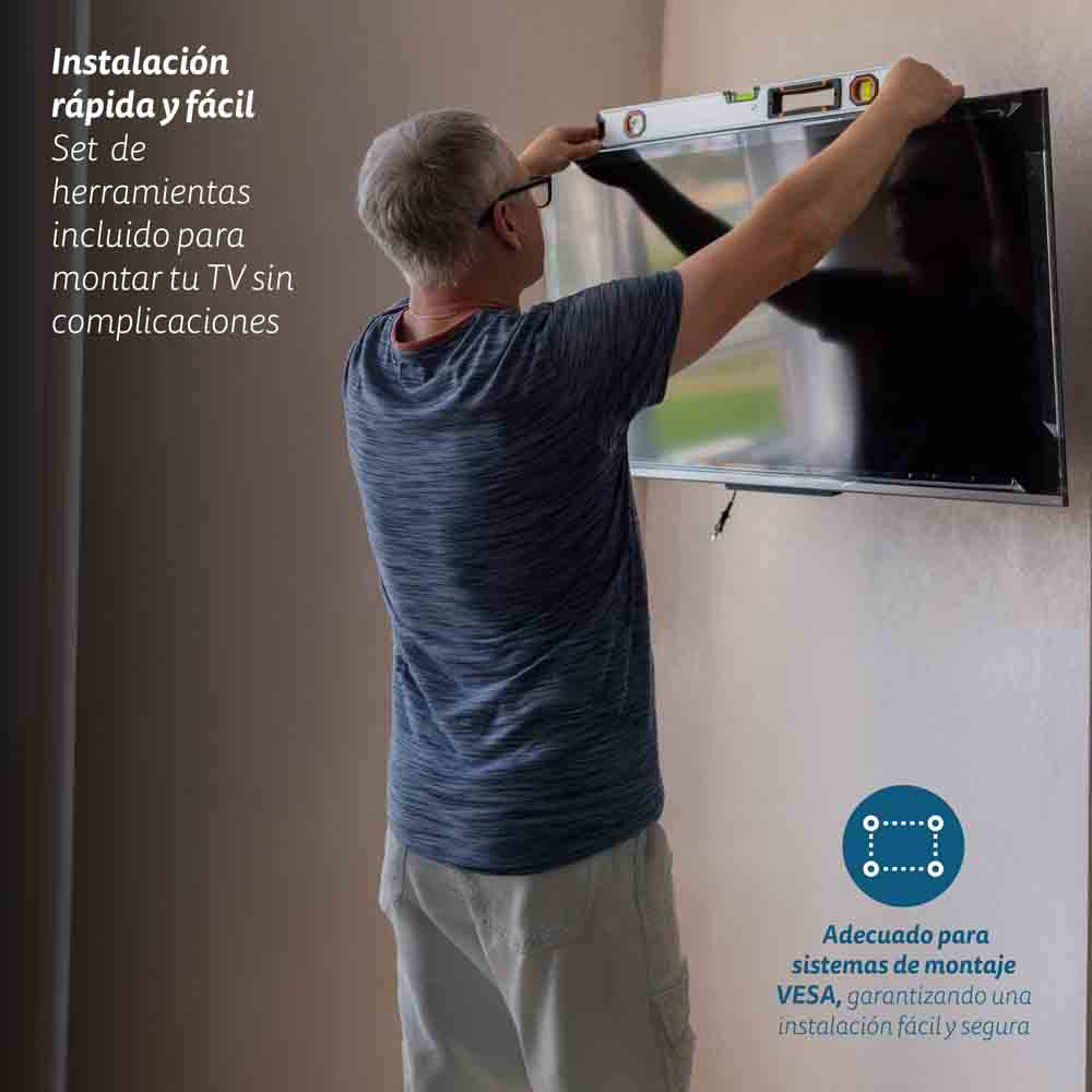 Persona instalando TV en pared, usando nivel.