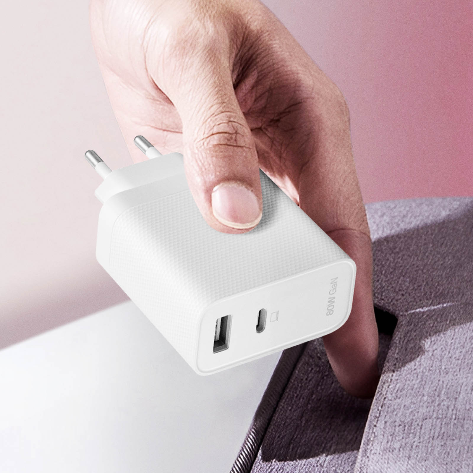 Dłoń trzyma białą ładowarkę GaN 60W z portami USB i USB-C.